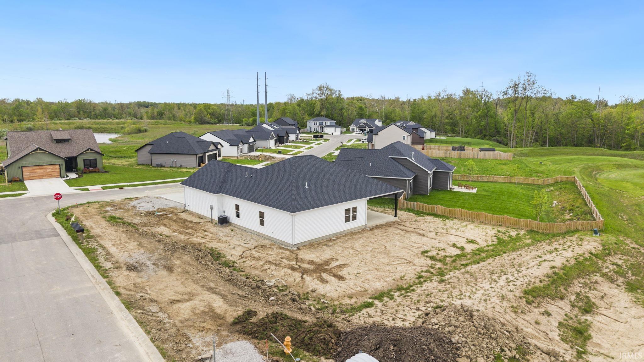 New construction residence featuring a white exterior, dark shingle roof, and a covered back patio