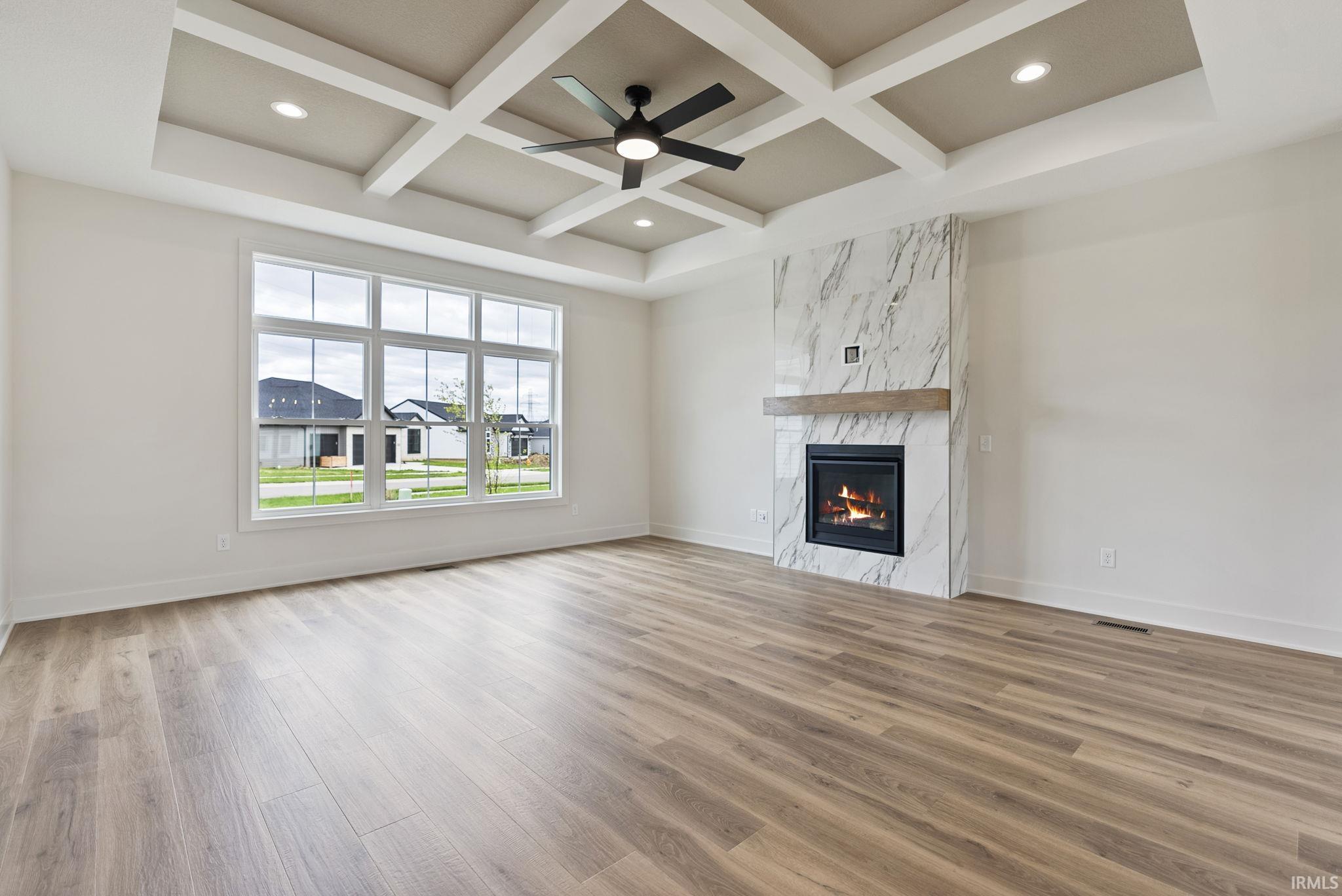 Spacious interior featuring wood-finish flooring, a contemporary fireplace with a marble-look surround and wood mantel, and large multi-pane windows