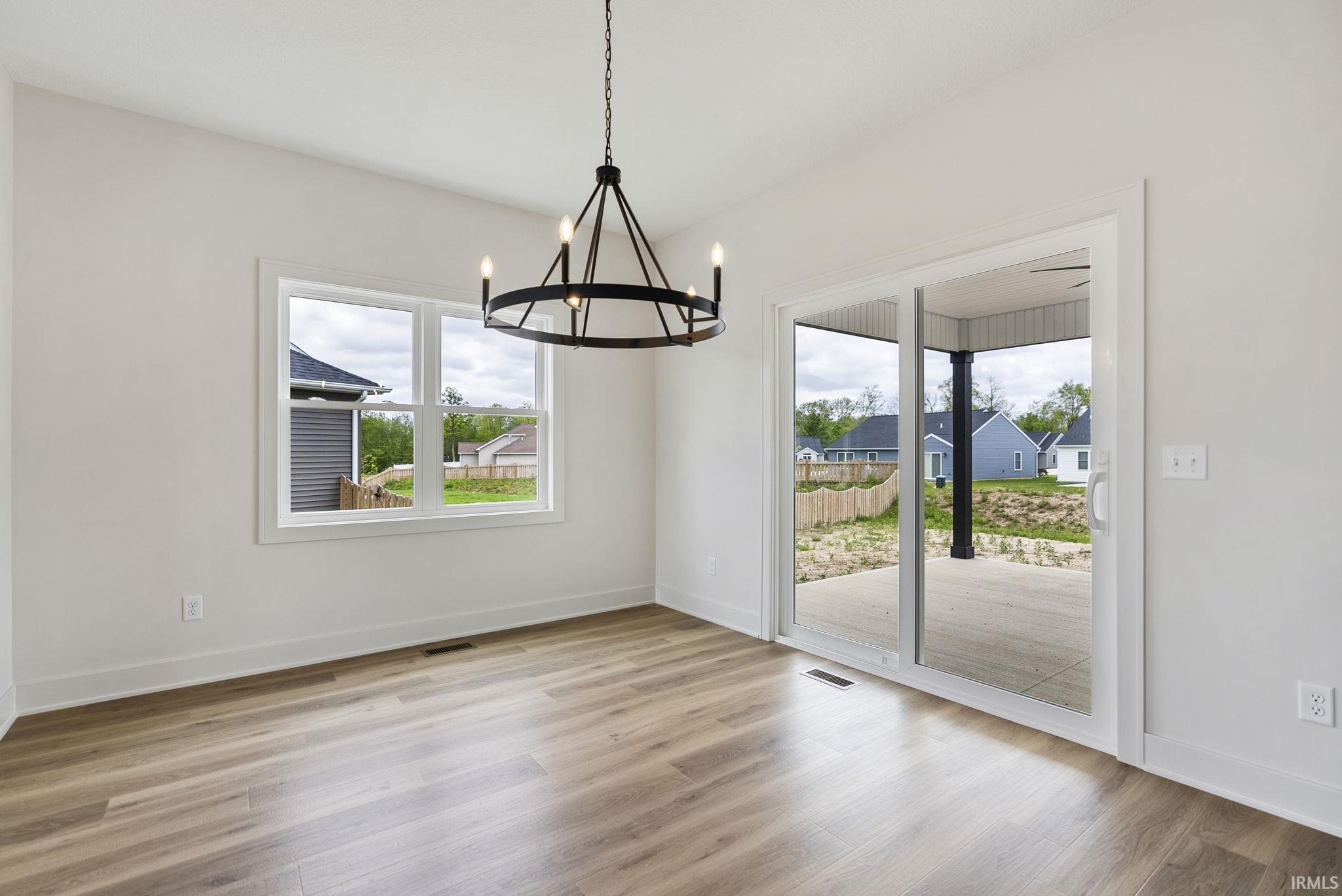 Open-concept room featuring wood-finish flooring, a contemporary black metal chandelier, and white trim