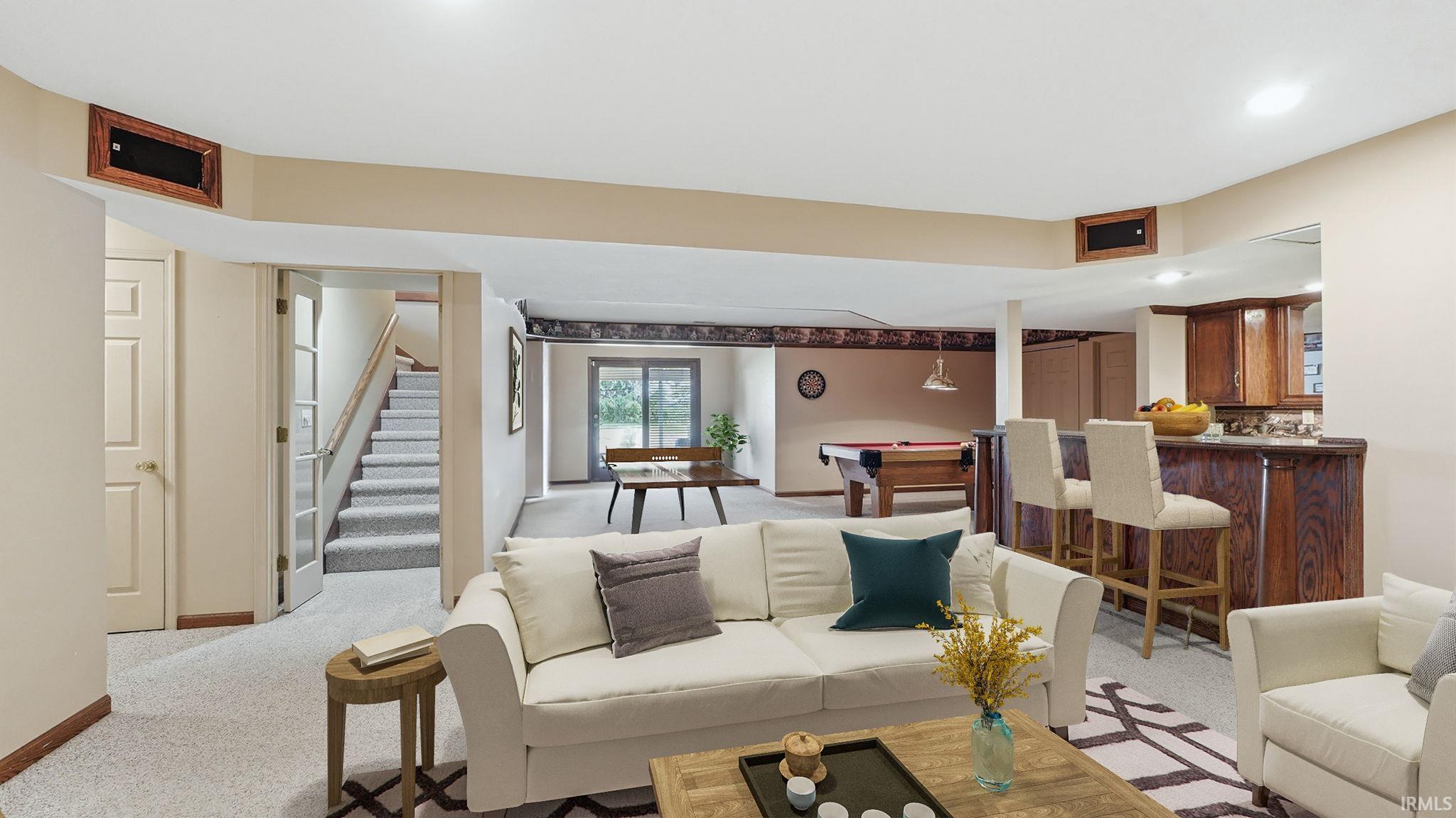 Finished lower level featuring a full staircase, wet bar with seating, built-in cabinetry, and sliding glass doors