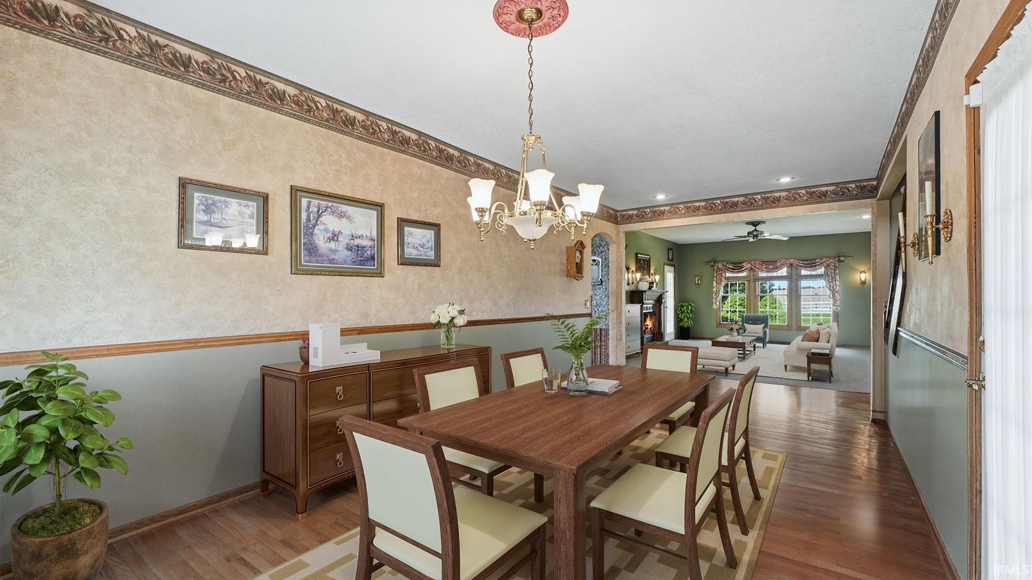 Dining area with wood-finish flooring, an ornate chandelier, and chair rail molding