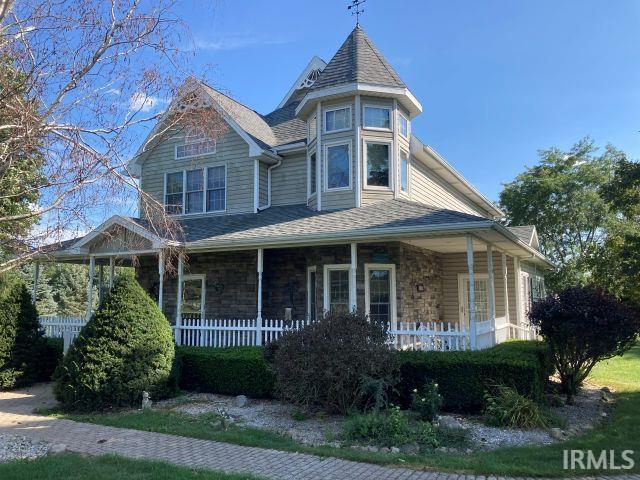 Two-story residence featuring a prominent turret with a weathervane and bay windows
