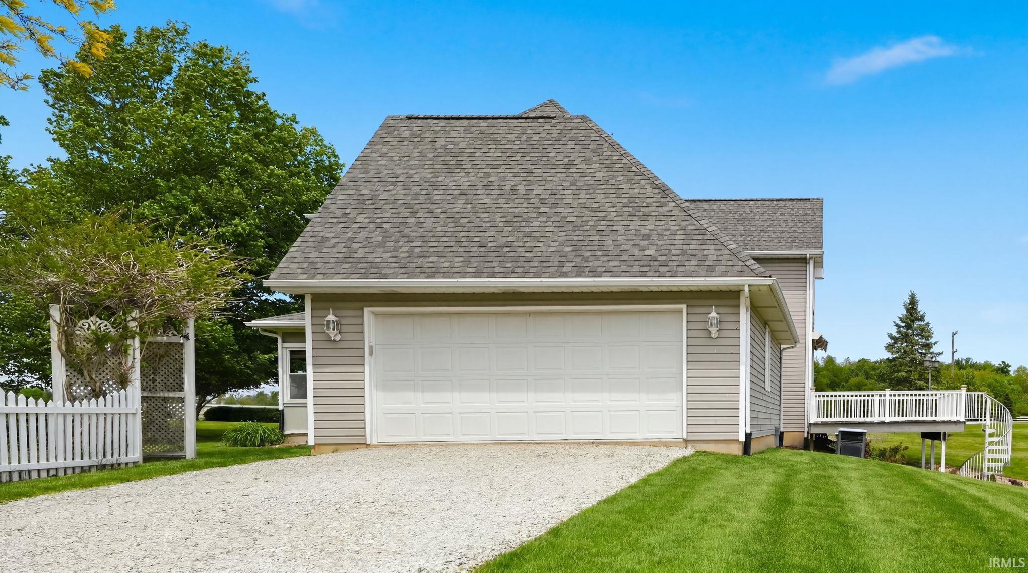 Attached two-car garage featuring a white panel door and exterior sconce lighting