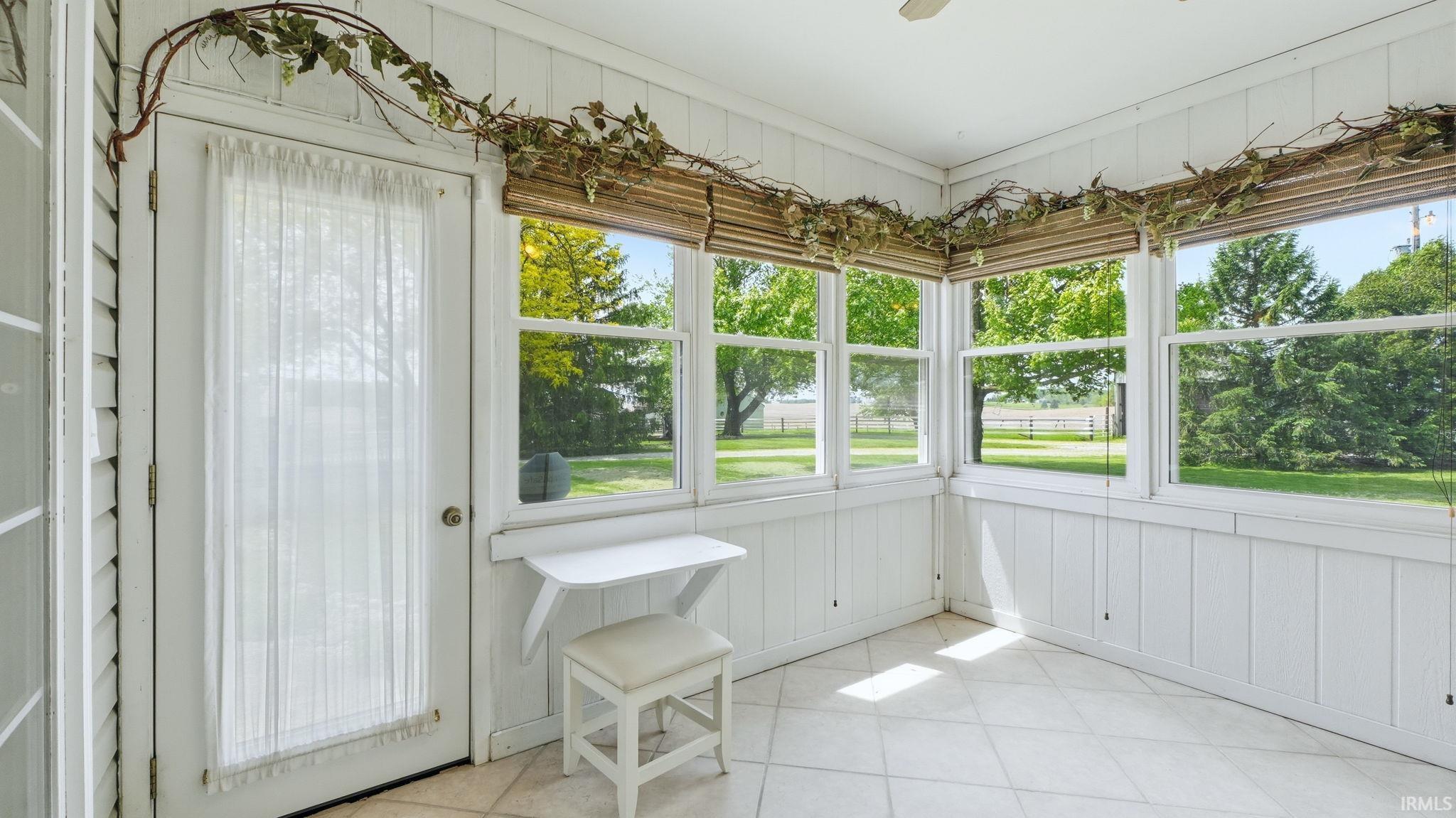 Sunroom featuring a wall of windows, white paneling, and tile flooring