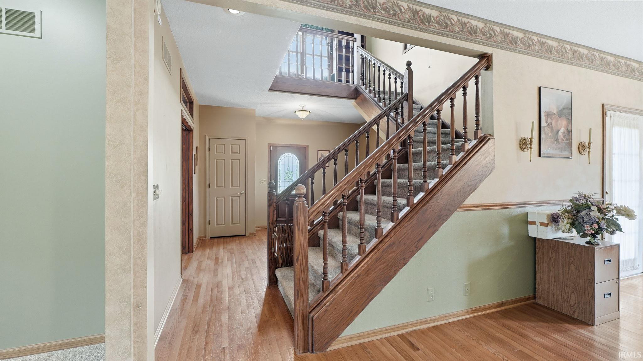 Entry foyer featuring a grand staircase with wood balusters and carpeted treads