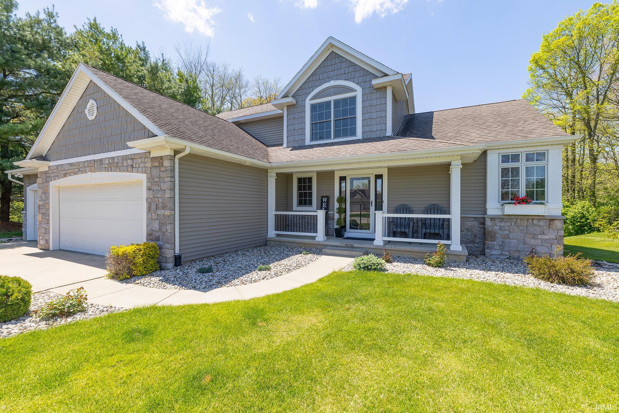 Two-story residence featuring a covered front porch, stone veneer accents, and a two-car garage