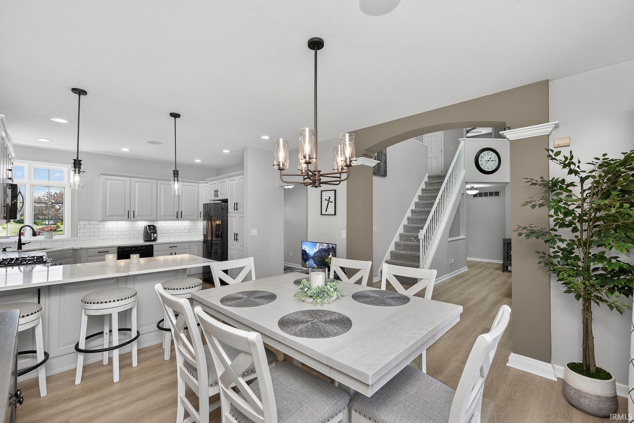 Open-concept dining area featuring wood-finish flooring, a contemporary chandelier, and direct access to the kitchen