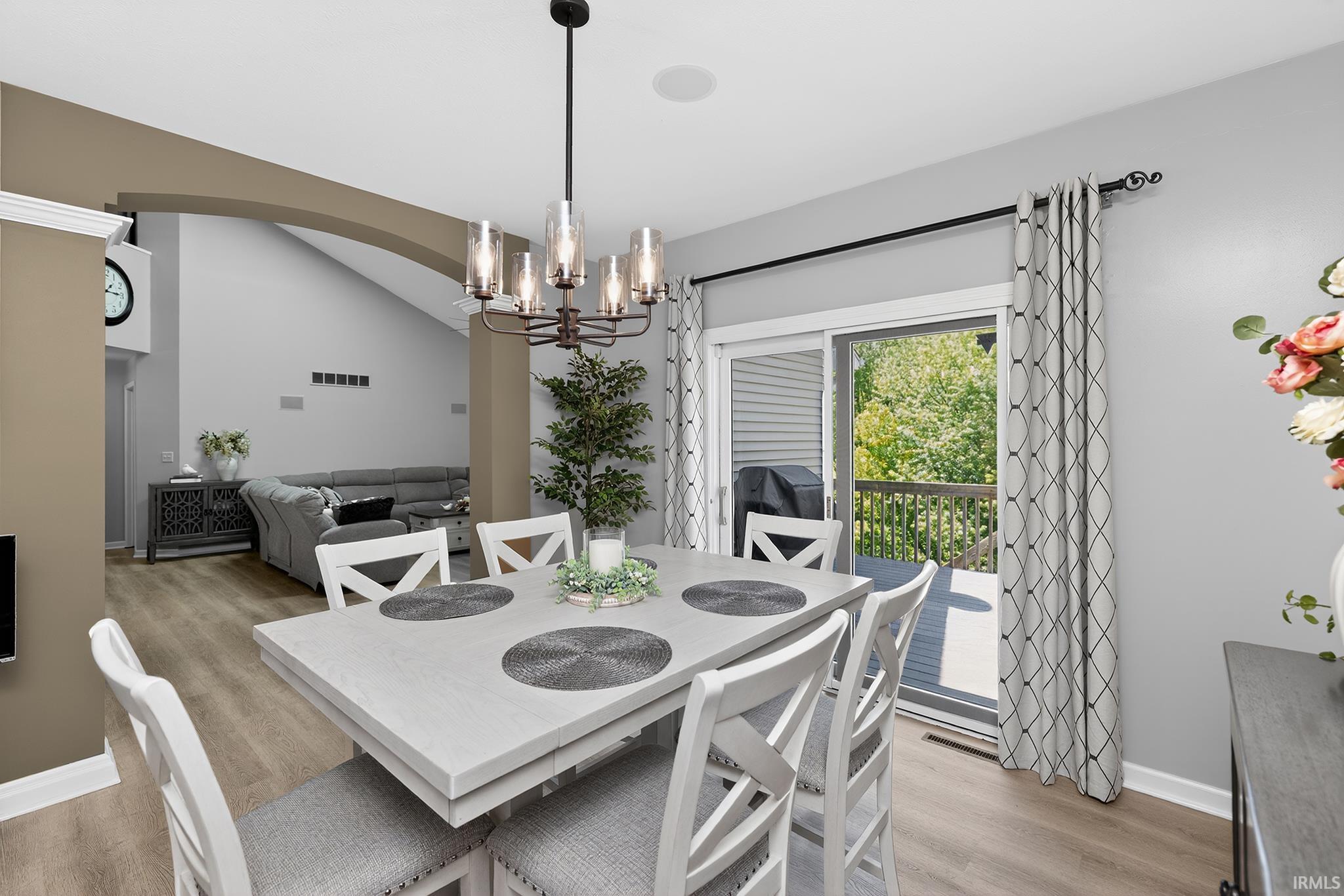 Dining area featuring a contemporary chandelier, wood-finish flooring, and a sliding glass door opening to an outdoor deck
