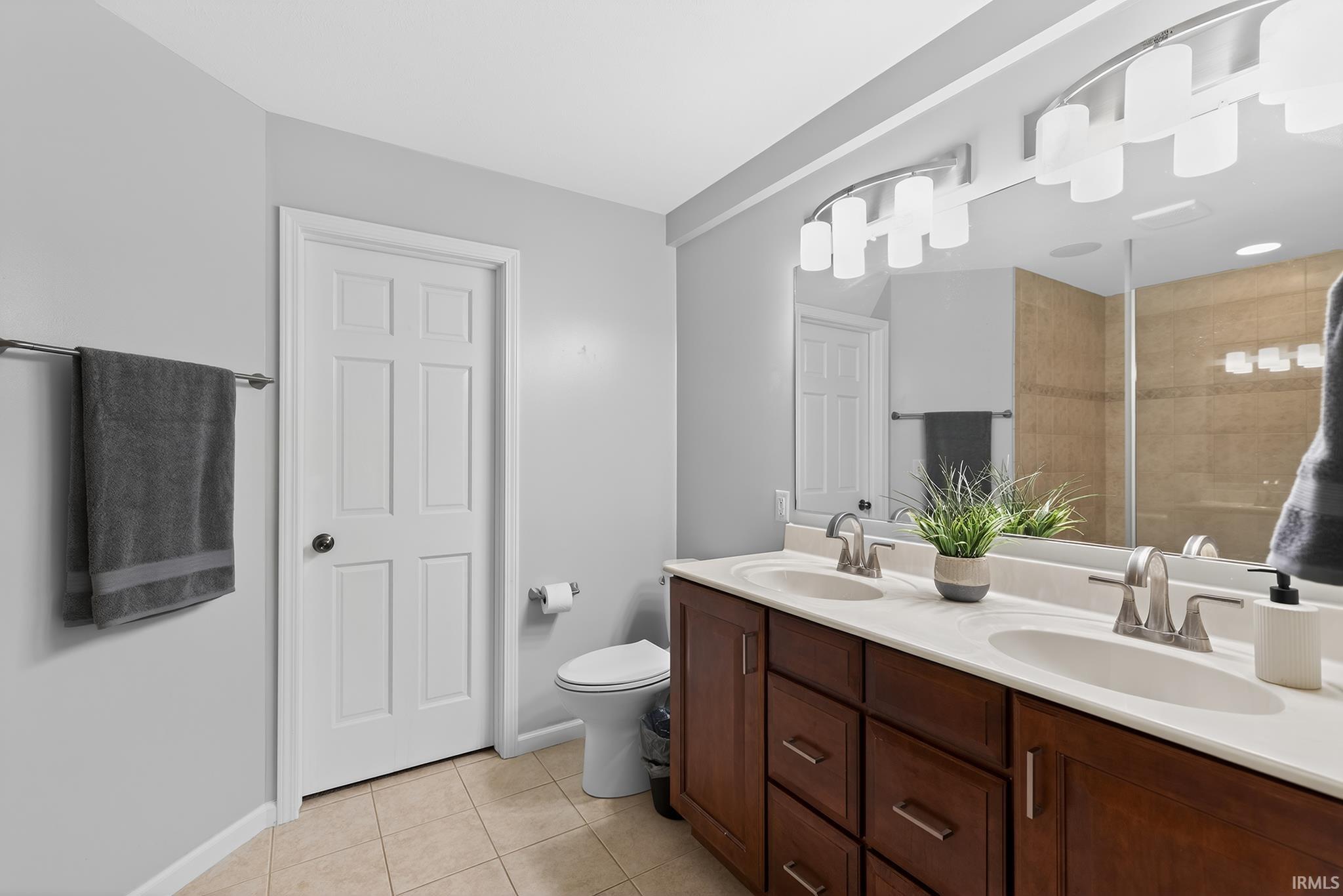 Dual vanity featuring wood-finish cabinetry, integrated white sinks, and brushed nickel fixtures