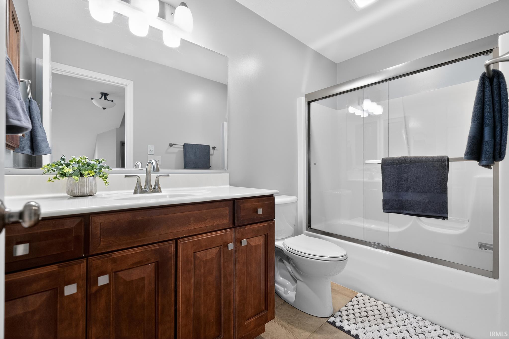 Bathroom featuring a wood-finish vanity with a white countertop and undermount sink