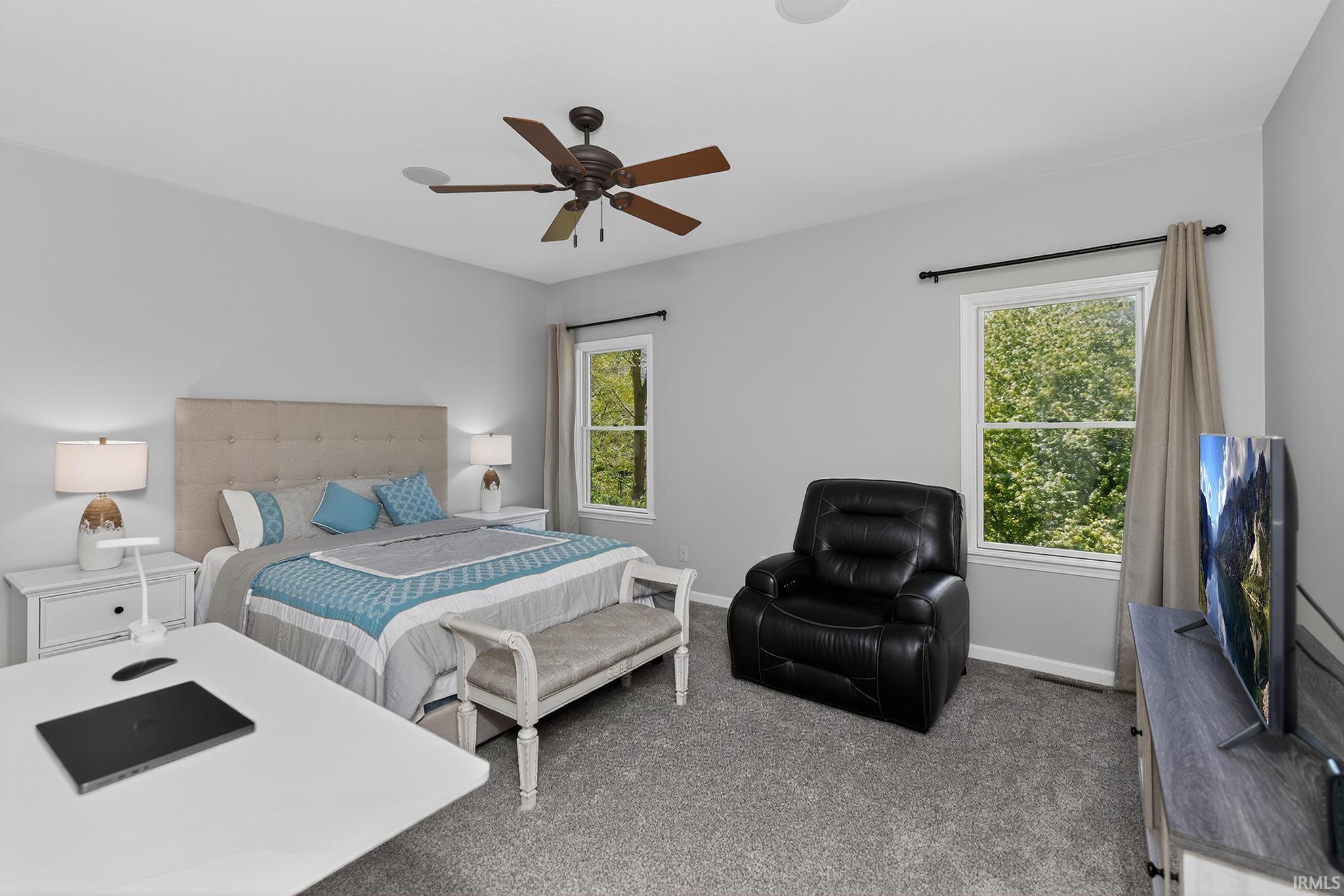 Carpeted room featuring light gray walls, two windows, and a ceiling fan with integrated lighting