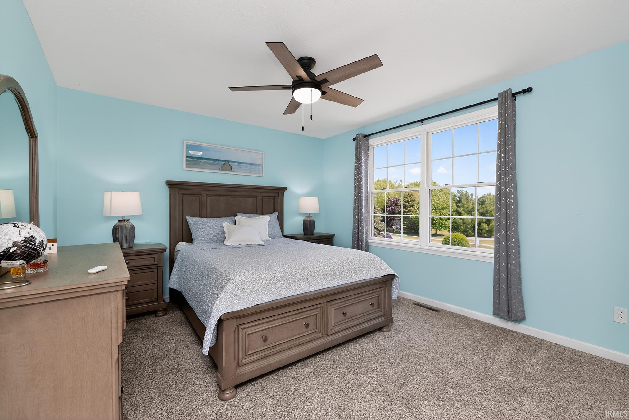 Bright room featuring a large window with multiple panes, ceiling fan light fixture, and carpet flooring