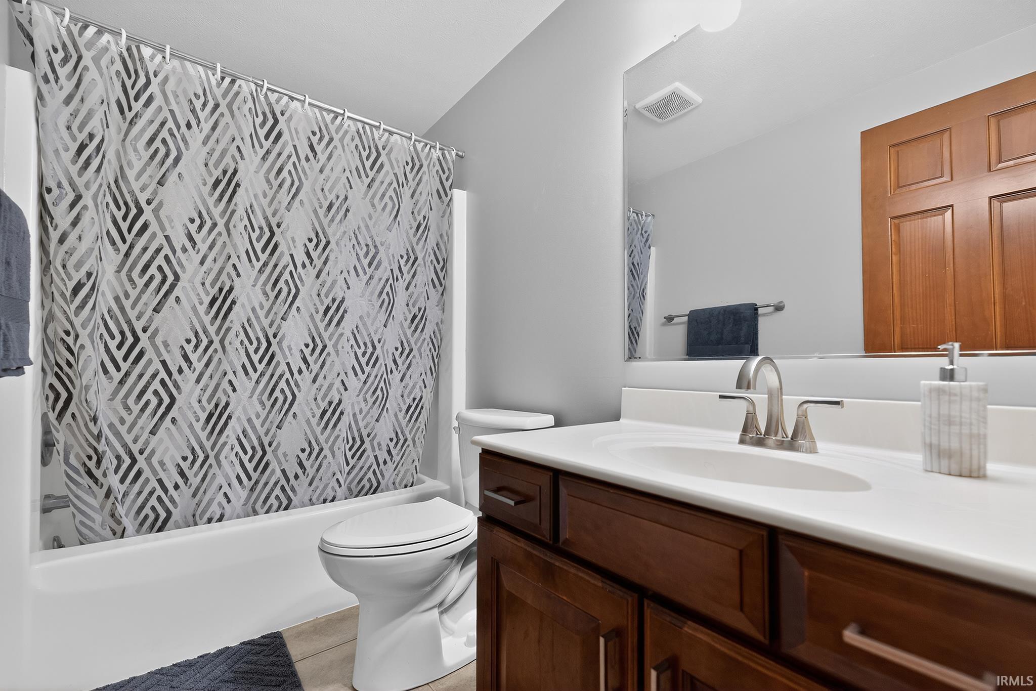 Bathroom featuring a white bathtub, toilet, and a dark wood-finish vanity with a white countertop and undermount sink