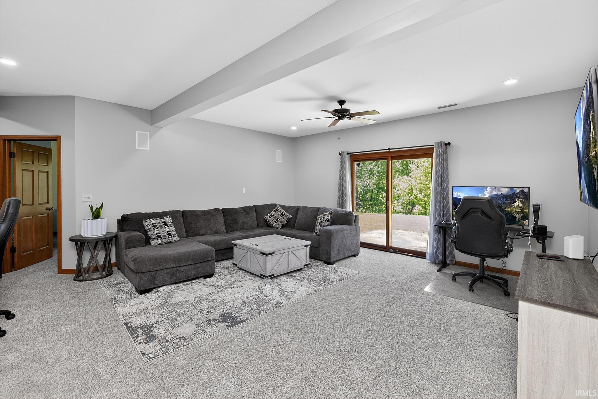 Spacious carpeted room featuring light gray walls, recessed lighting, and a ceiling fan