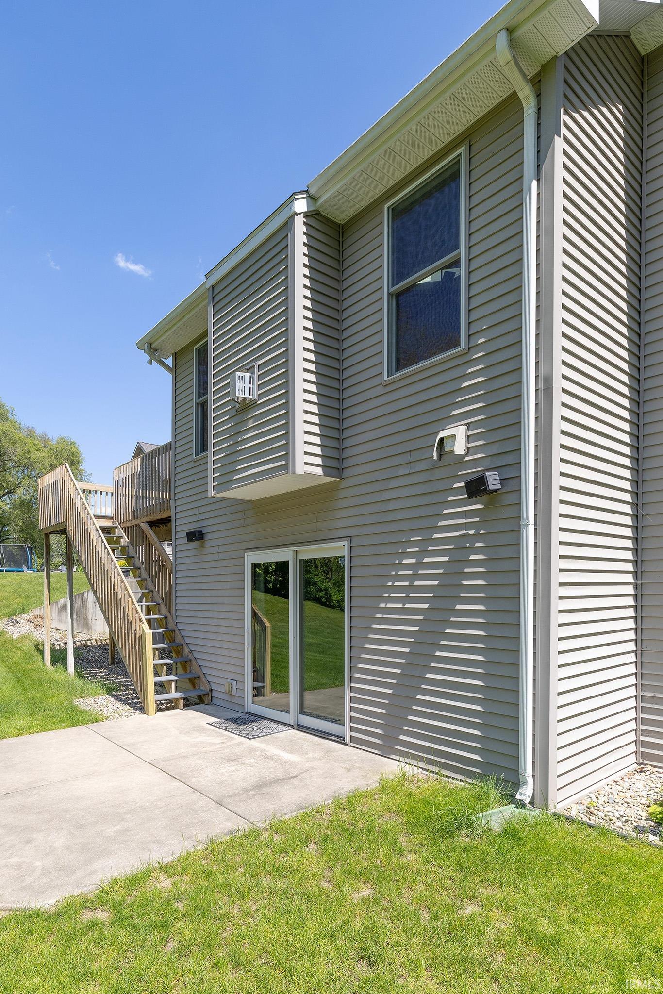 Exterior featuring horizontal siding, a concrete patio, sliding glass doors, and a wooden deck with stairs