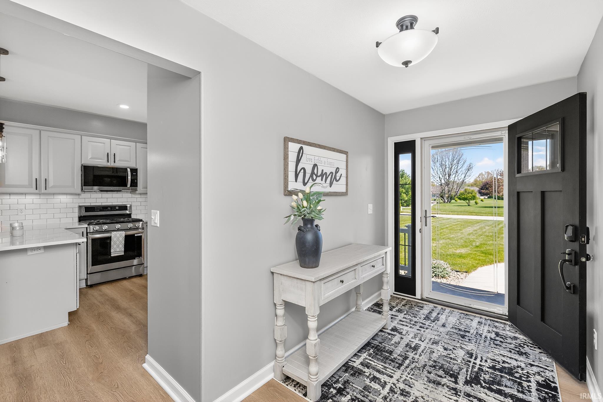 Entryway featuring a black craftsman-style front door with frosted glass, wood-finish flooring, and light gray wall paint