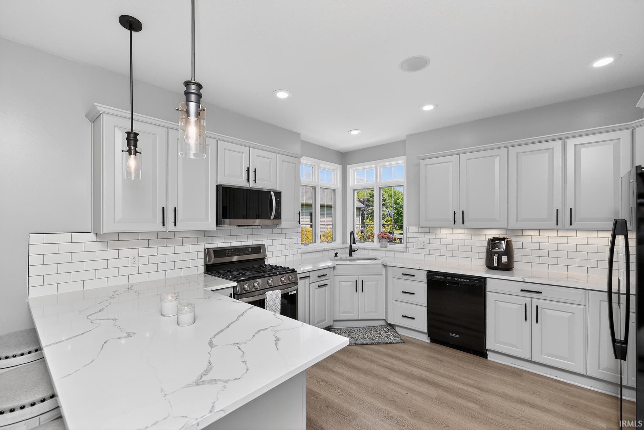 Kitchen with light cabinetry, white subway tile backsplash, and light wood-finish flooring