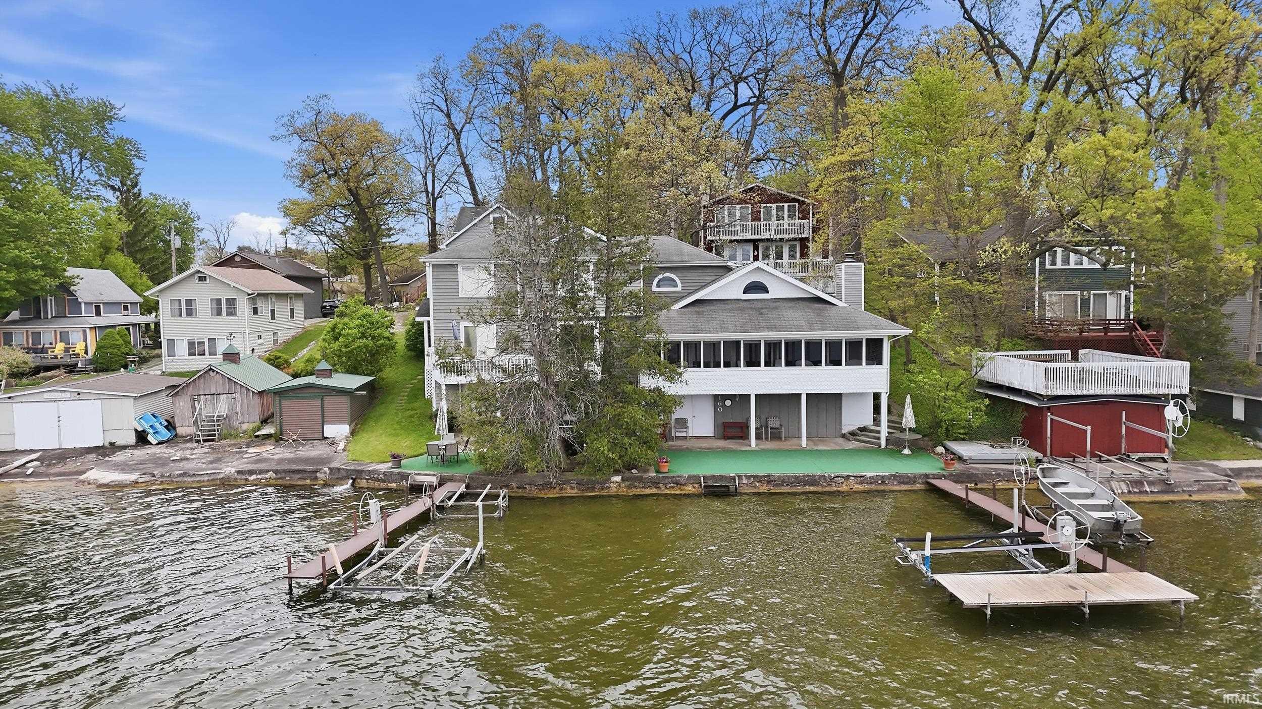 Waterfront property featuring a multi-level structure with a covered porch and an arched window dormer