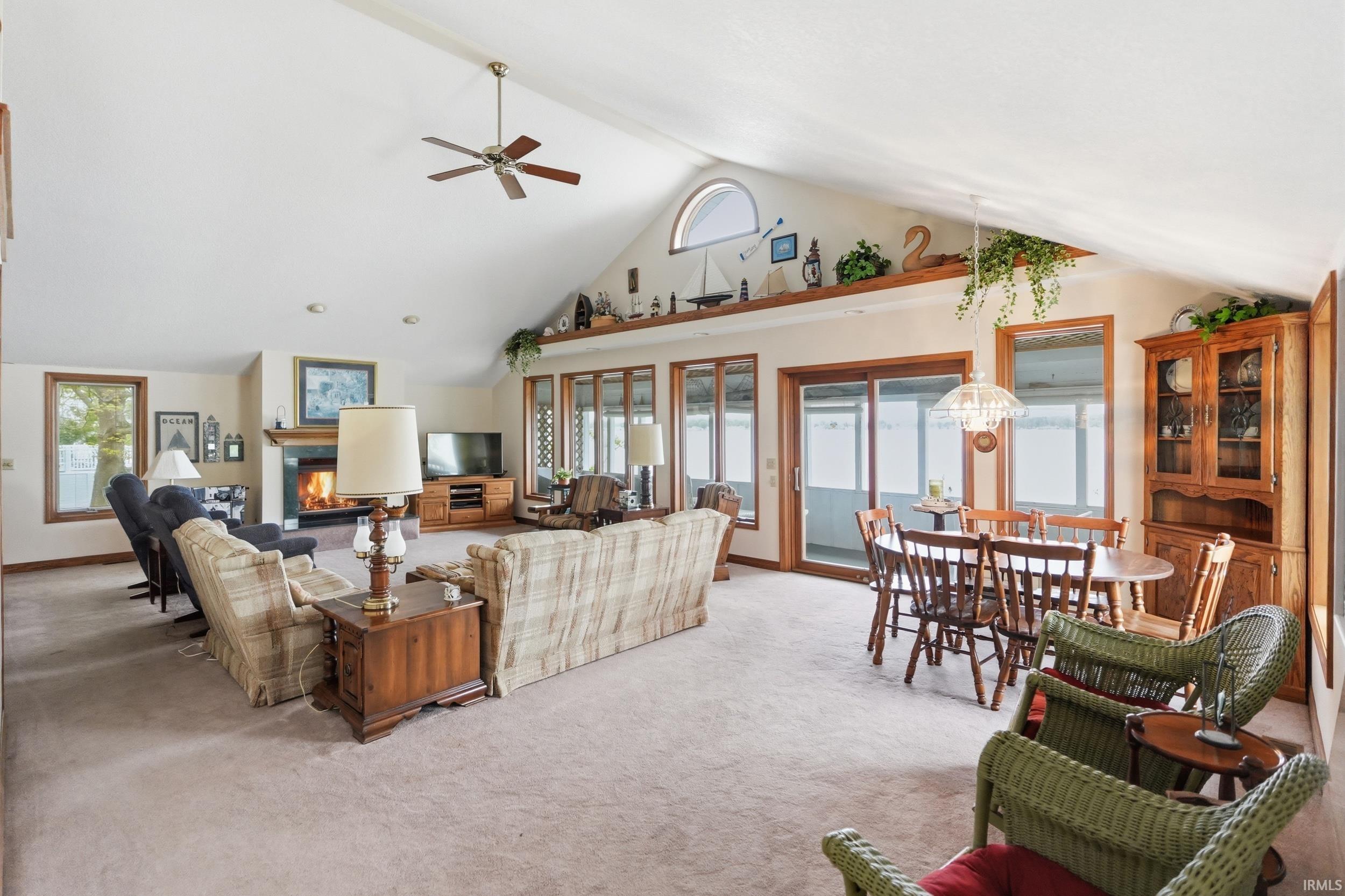 Vaulted ceiling great room with a fireplace, ceiling fan, and carpeted flooring