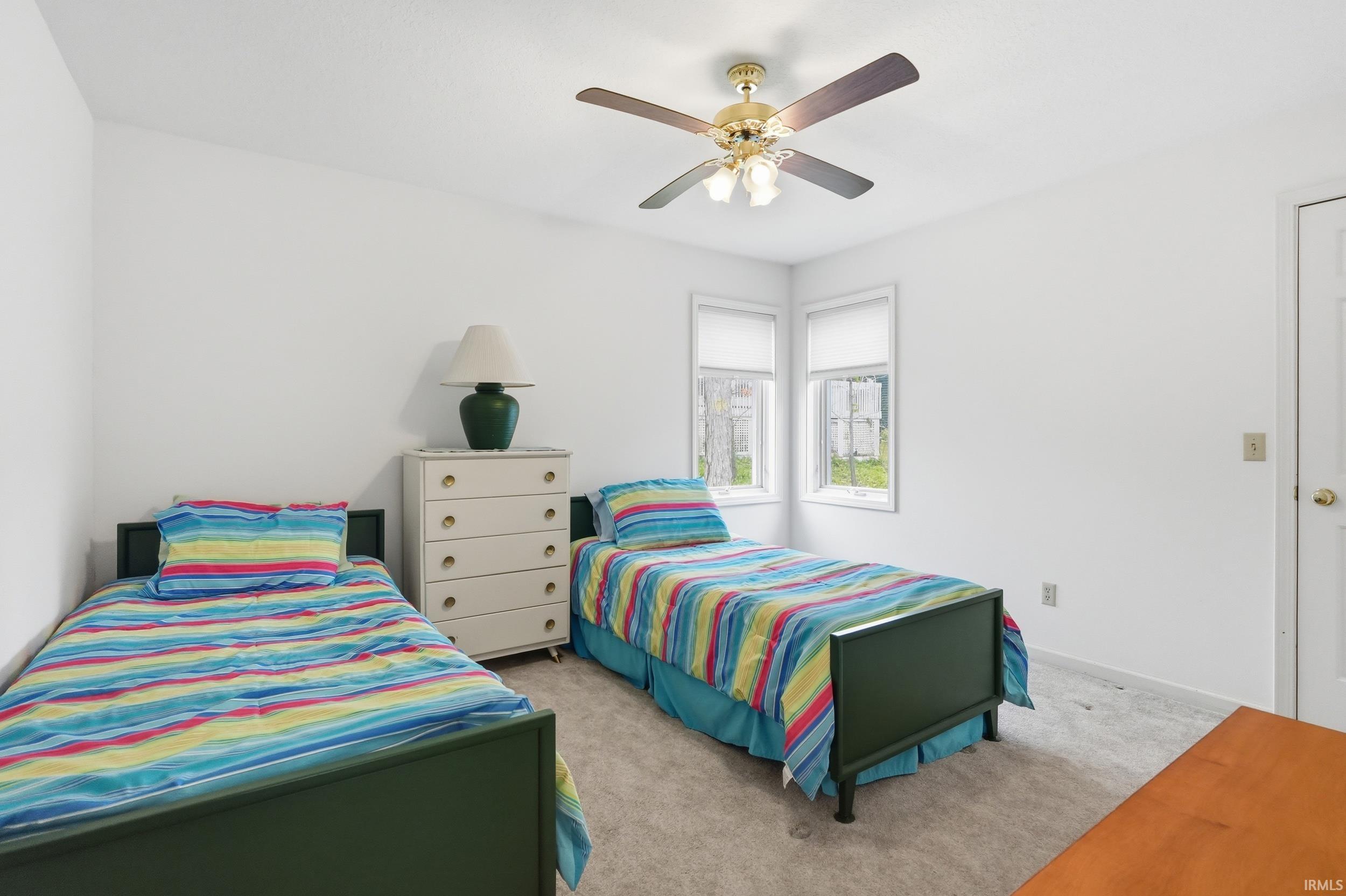 Light-filled room featuring neutral wall tones, two windows with roller shades, and a ceiling fan with integrated lighting