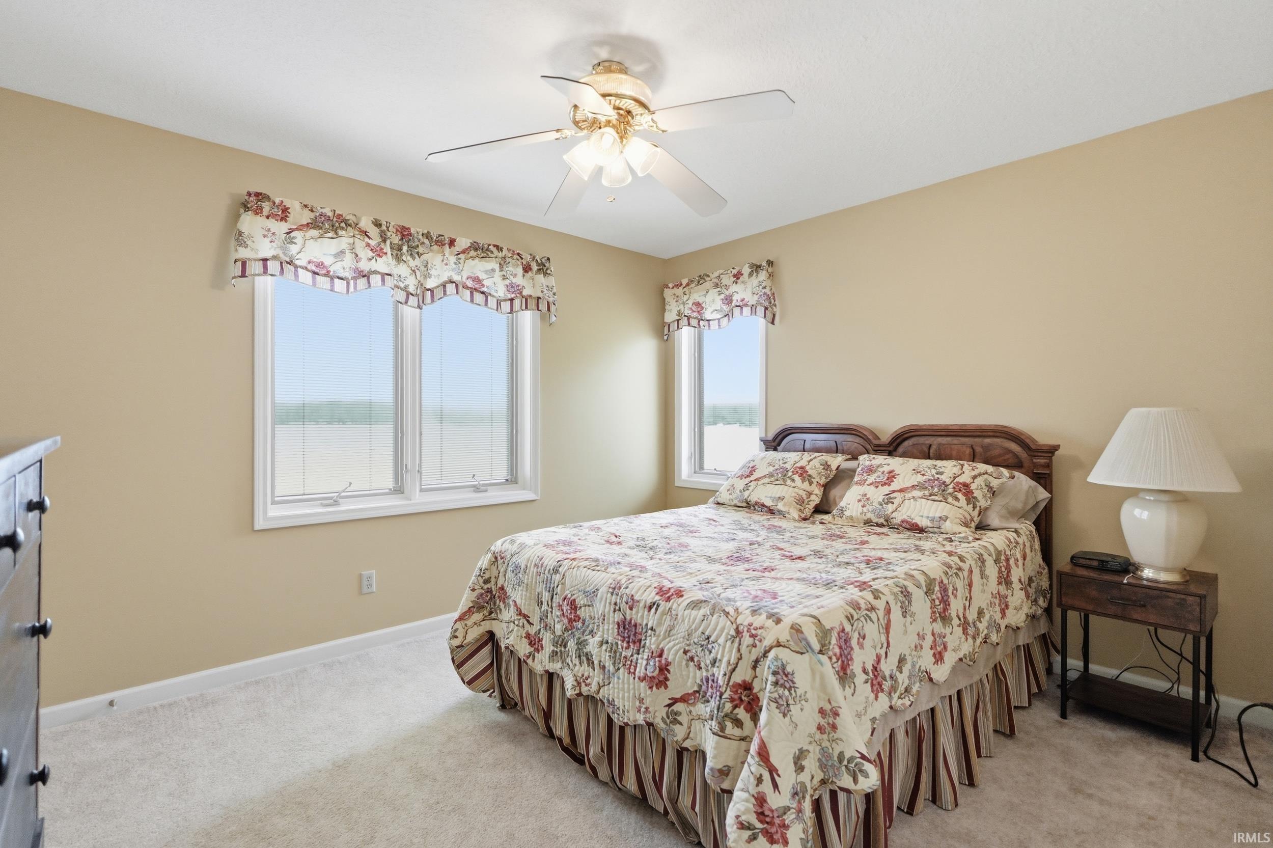 Carpeted room featuring multiple windows, a ceiling fan with integrated lighting, and neutral-toned walls