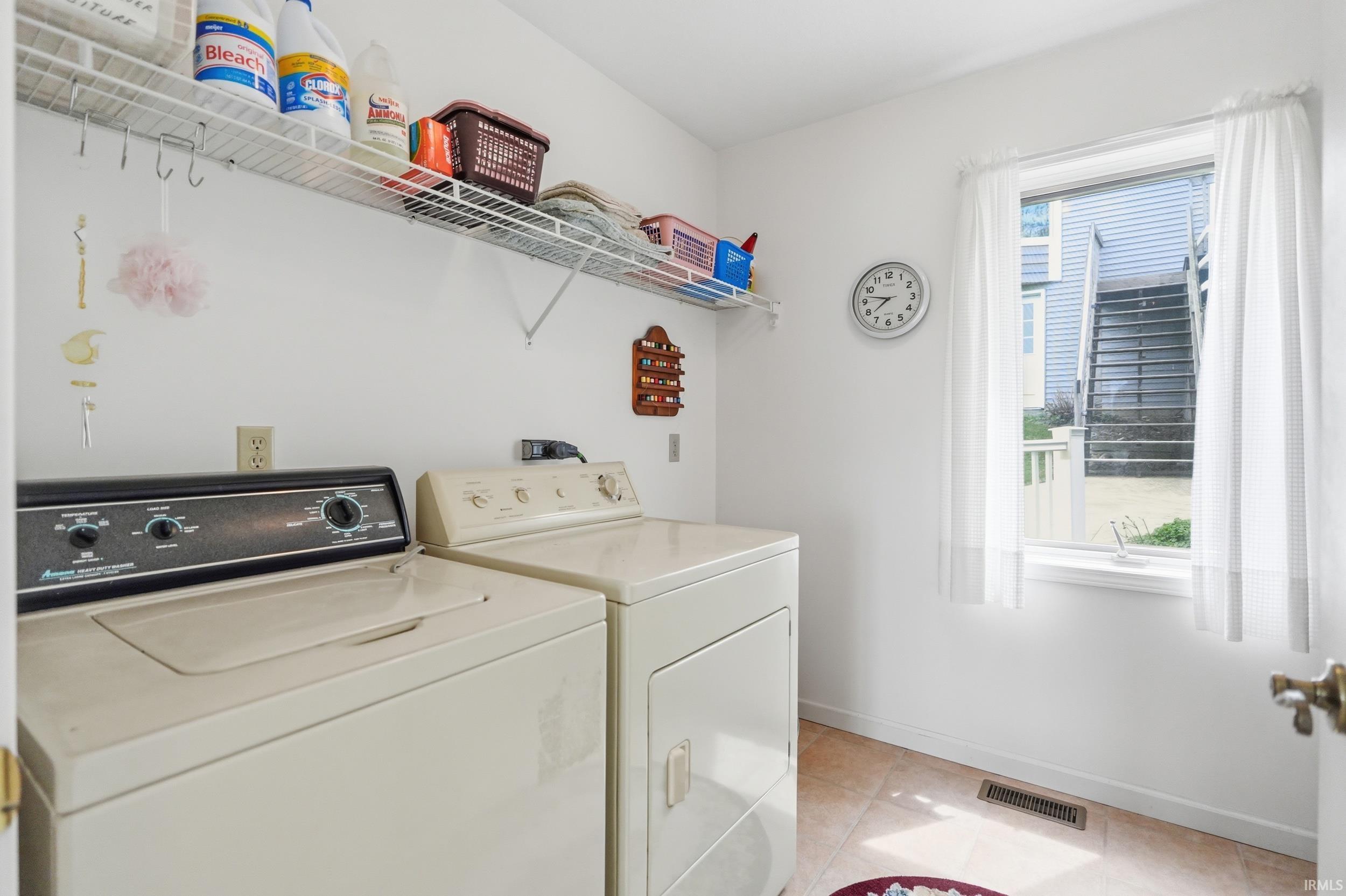 Dedicated laundry area featuring a wire rack shelving system, single window, and a tile floor