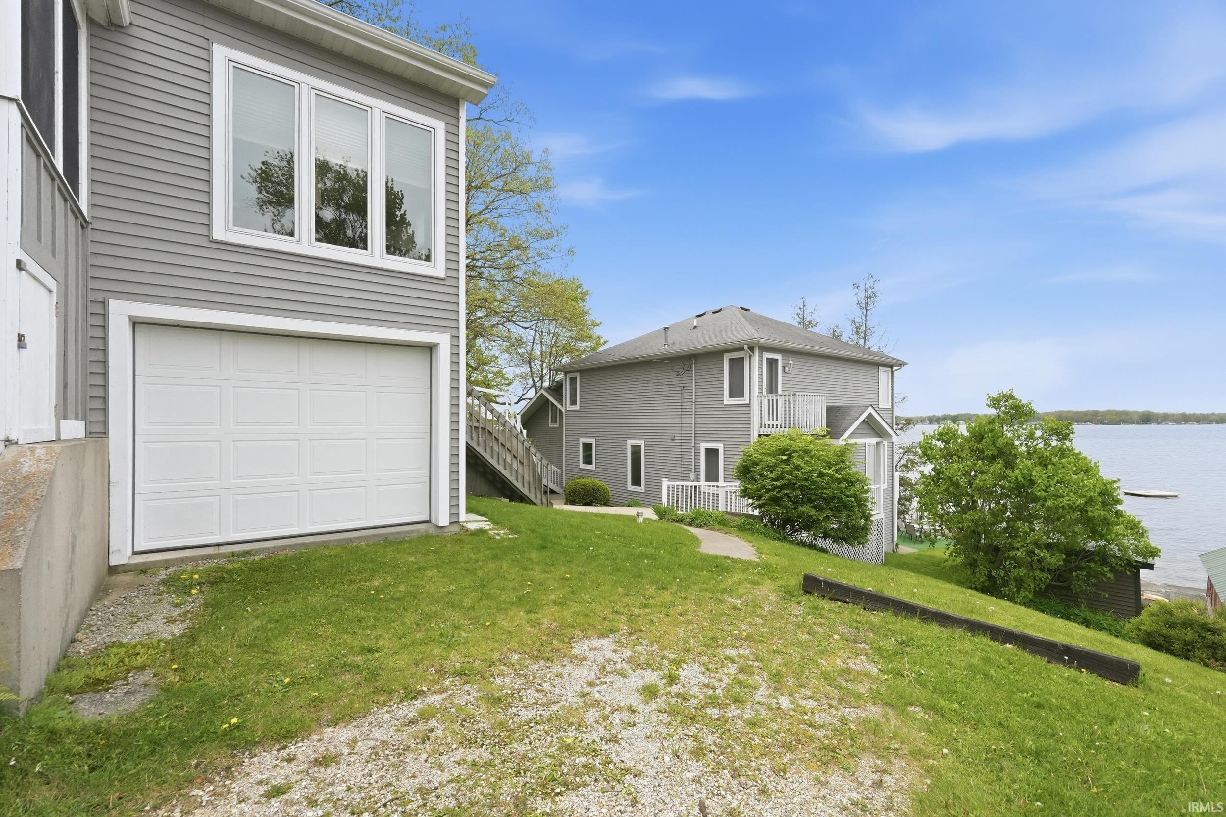Two-story residence with gray siding, white trim, and a prominent white paneled garage door