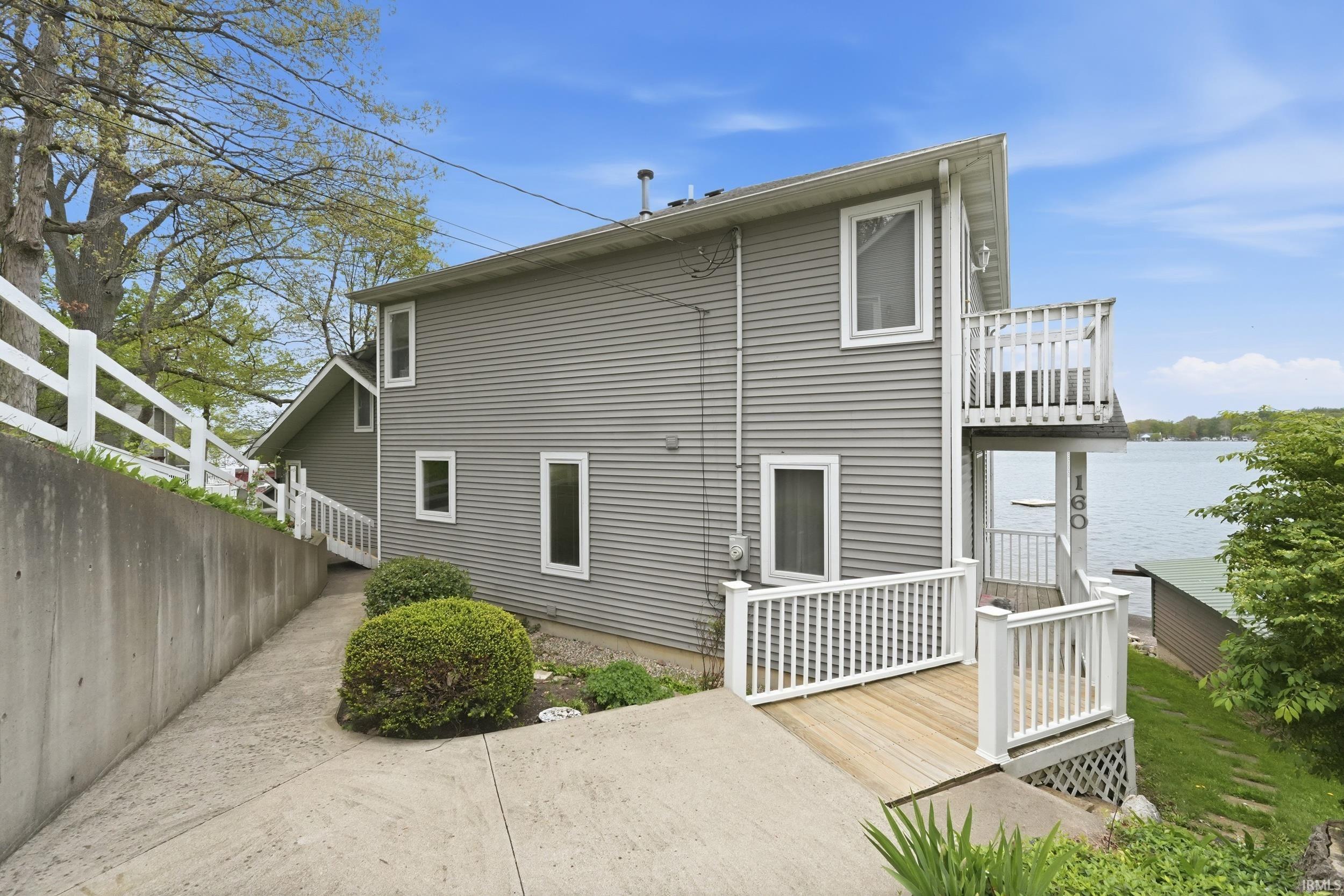Siding exterior with multiple windows, featuring a ground-level deck and an upper-level balcony