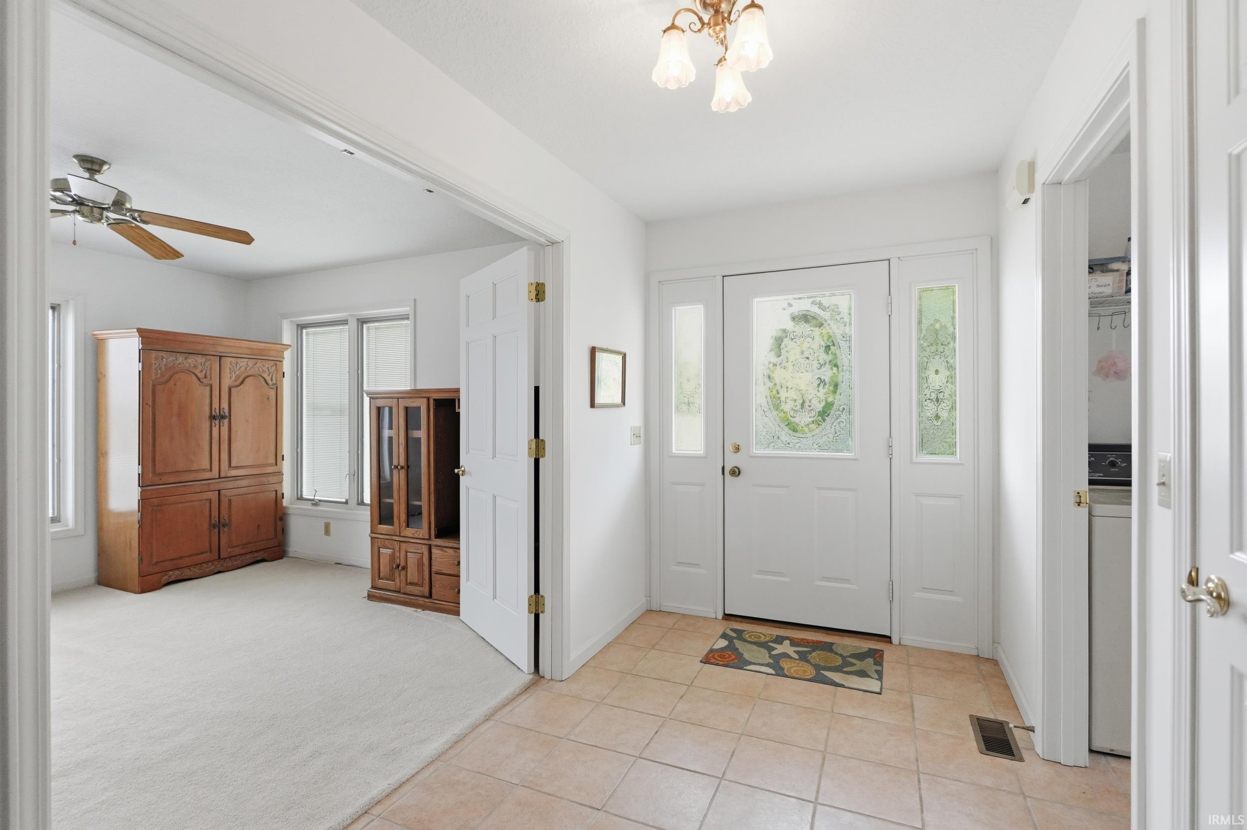 Entryway featuring tiled flooring, a white front door with decorative glass, and two sidelight windows