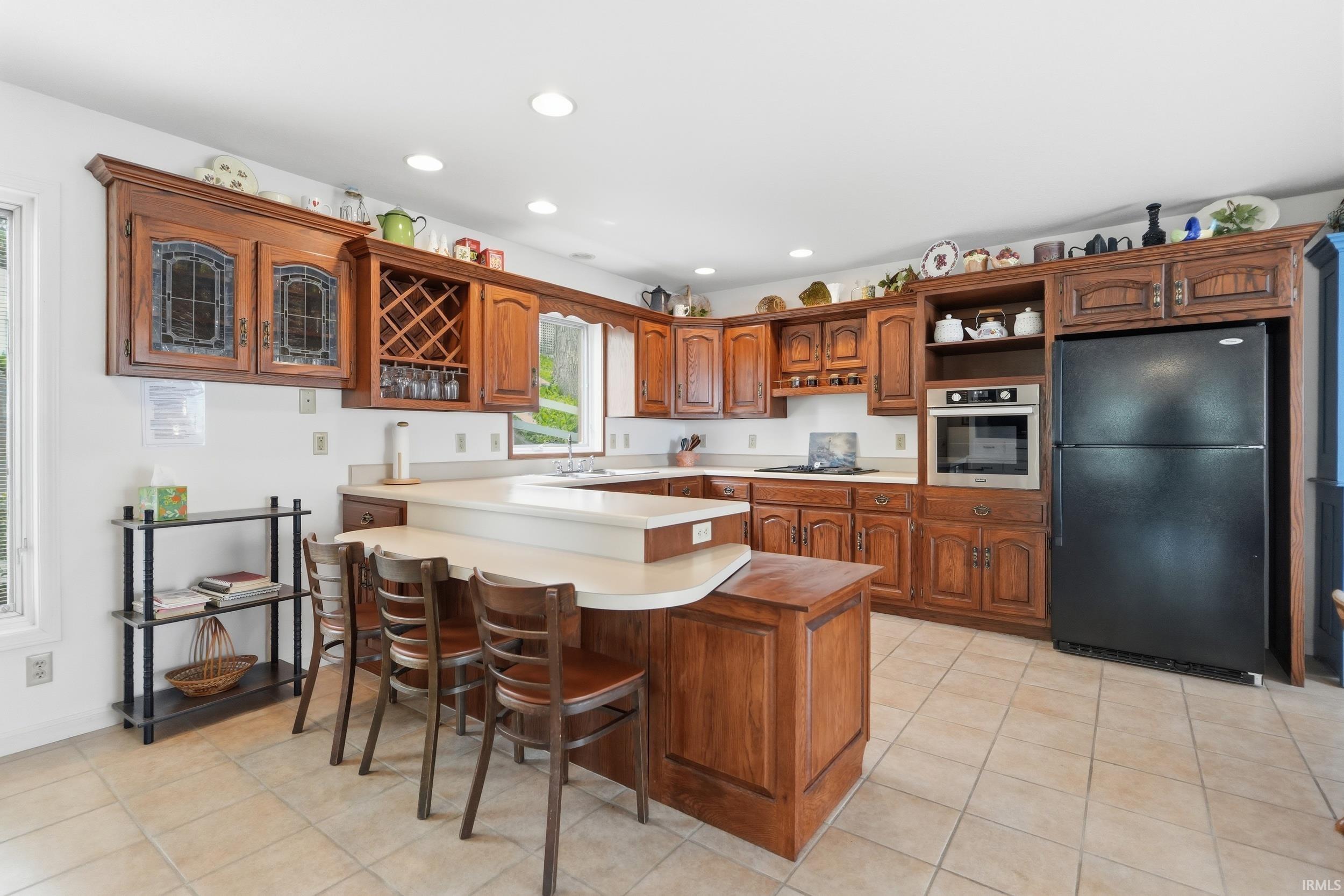 Kitchen featuring wood cabinetry, an integrated wine rack, a built-in oven, and a breakfast bar with seating