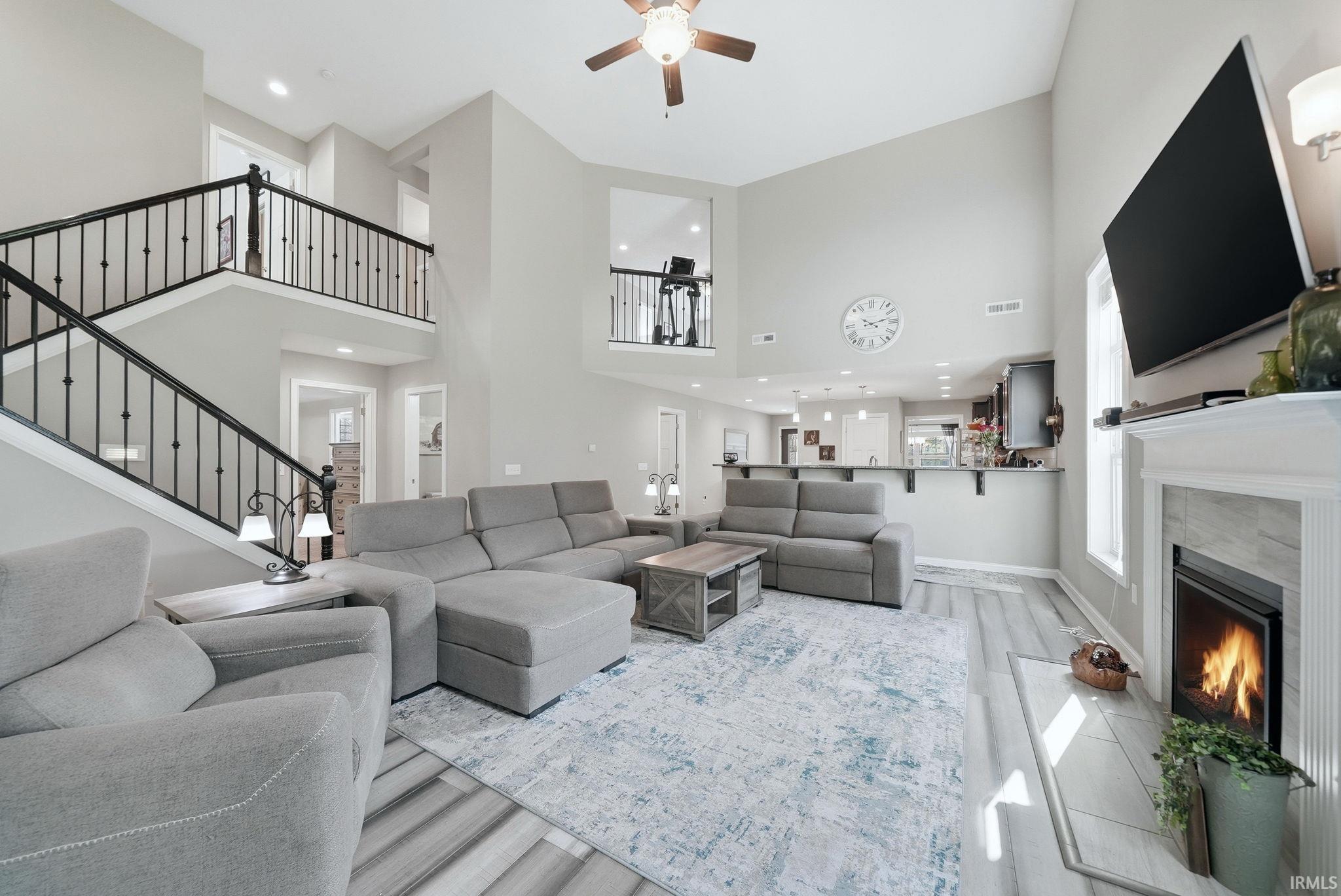 Vaulted living area featuring wood-finish flooring, a fireplace with a light-toned tile surround and white mantel, and an open concept layout