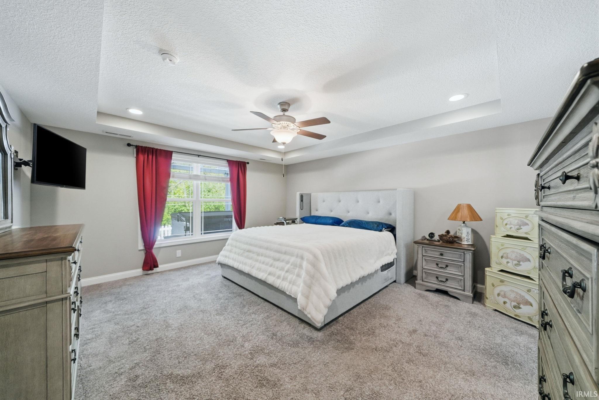 Carpeted room featuring a ceiling fan, recessed lighting, and a tray ceiling