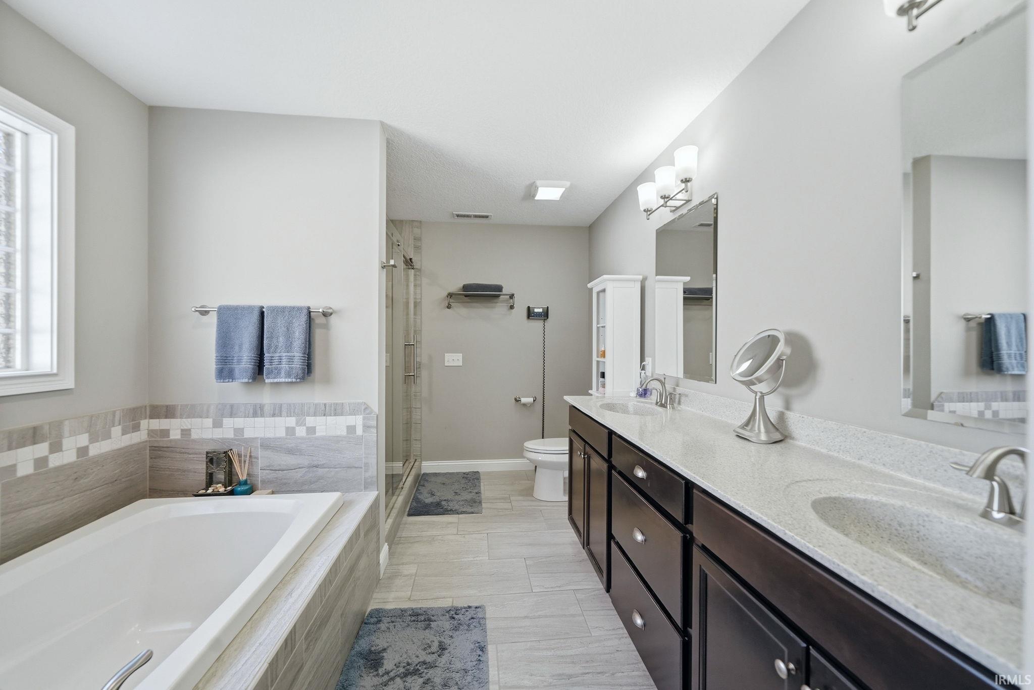 Bathroom featuring a double vanity with stone-finish countertops, deep-toned cabinetry, and individual mirrors