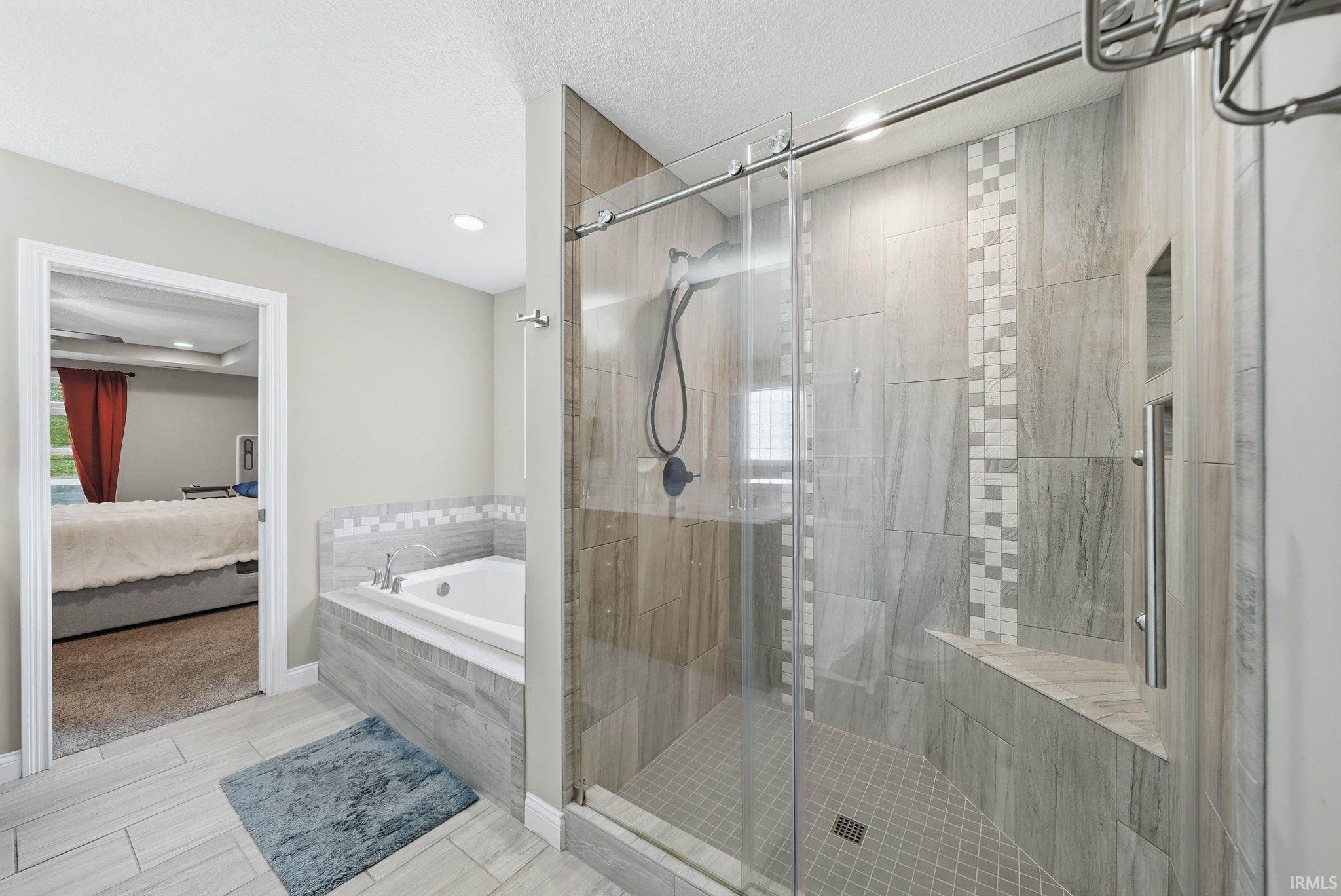 Shower featuring a glass sliding door, built-in bench, and tiled walls with decorative mosaic accents