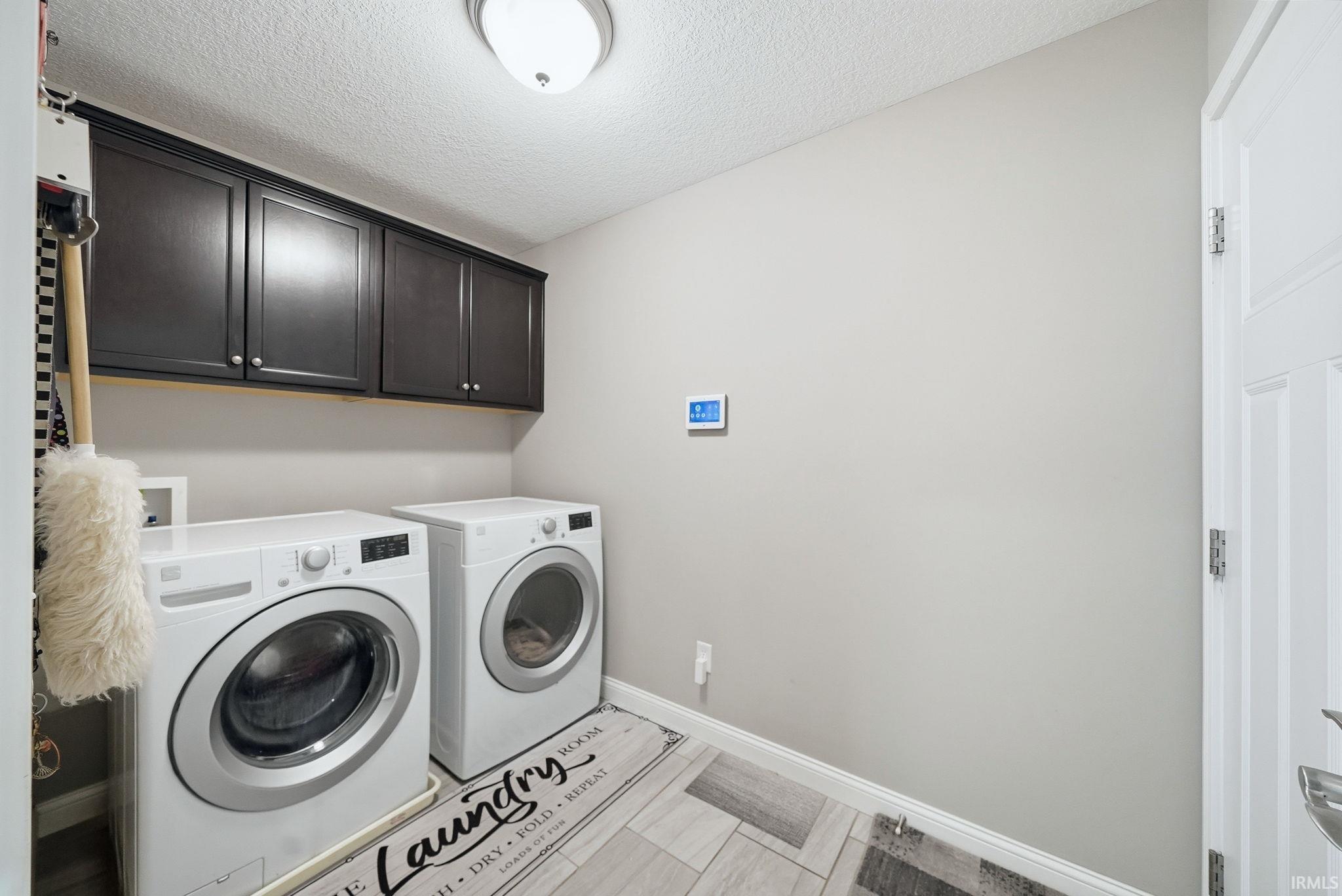 Laundry area featuring upper cabinetry, light-toned wall paint, and wood-finish flooring