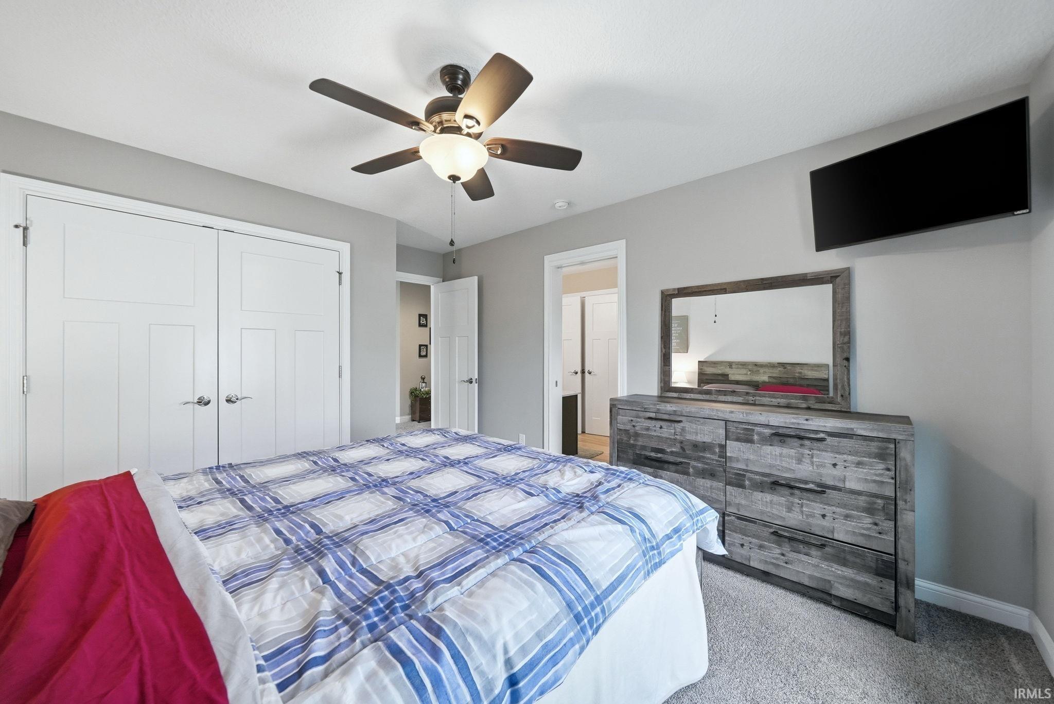 Bedroom featuring light gray walls, plush carpet, and a ceiling fan with integrated lighting