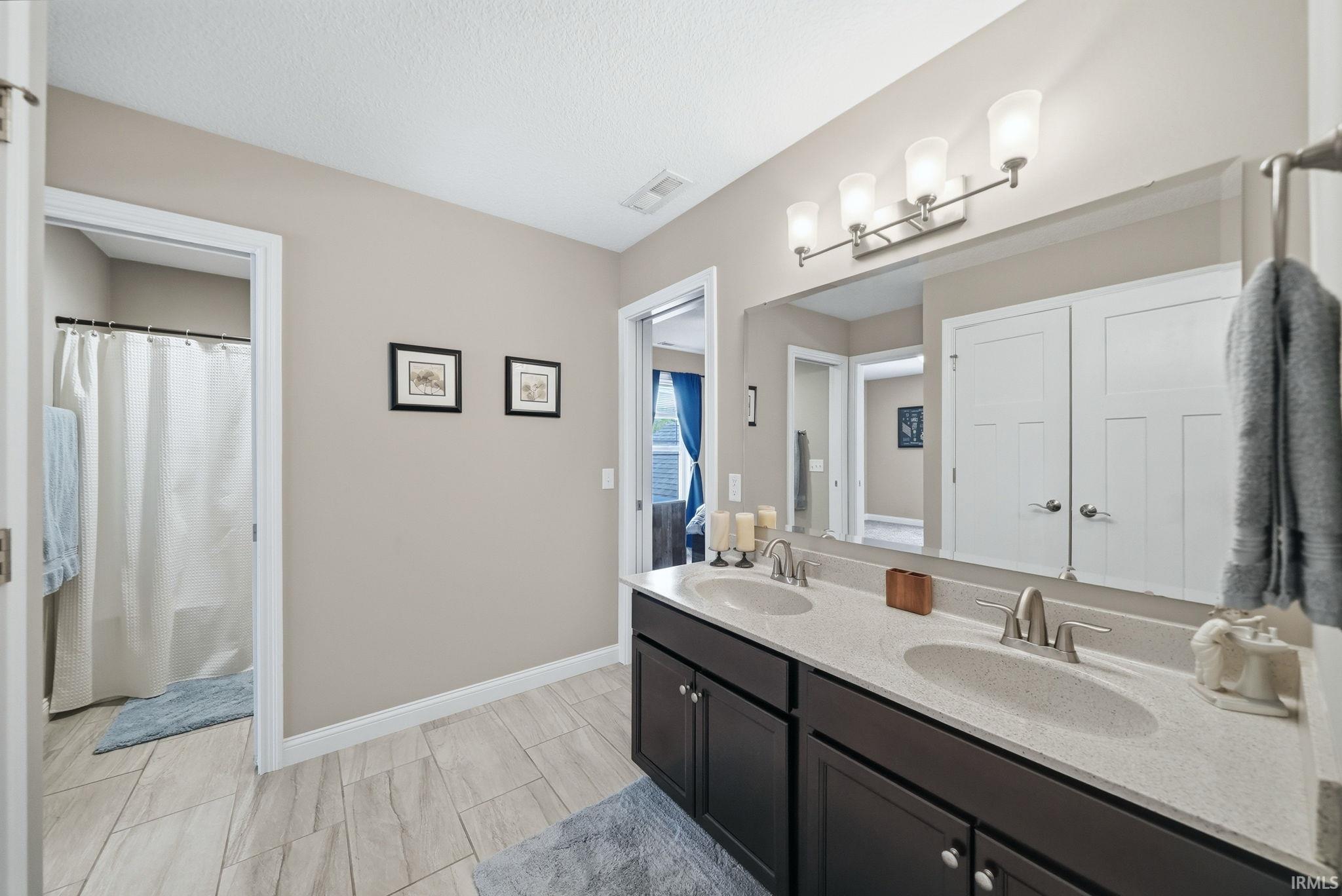 Bathroom featuring a double vanity with dark wood-finish cabinetry, light-toned countertops, and dual oval sinks