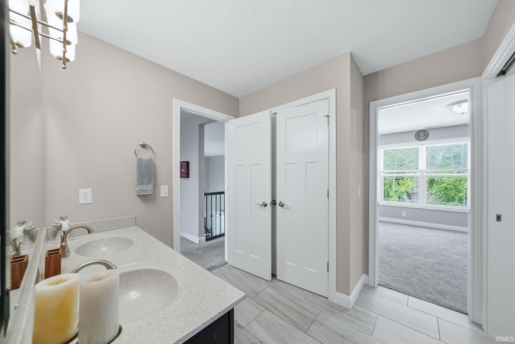 Bathroom vanity featuring a dual sink, light-toned countertop, and brushed nickel faucets