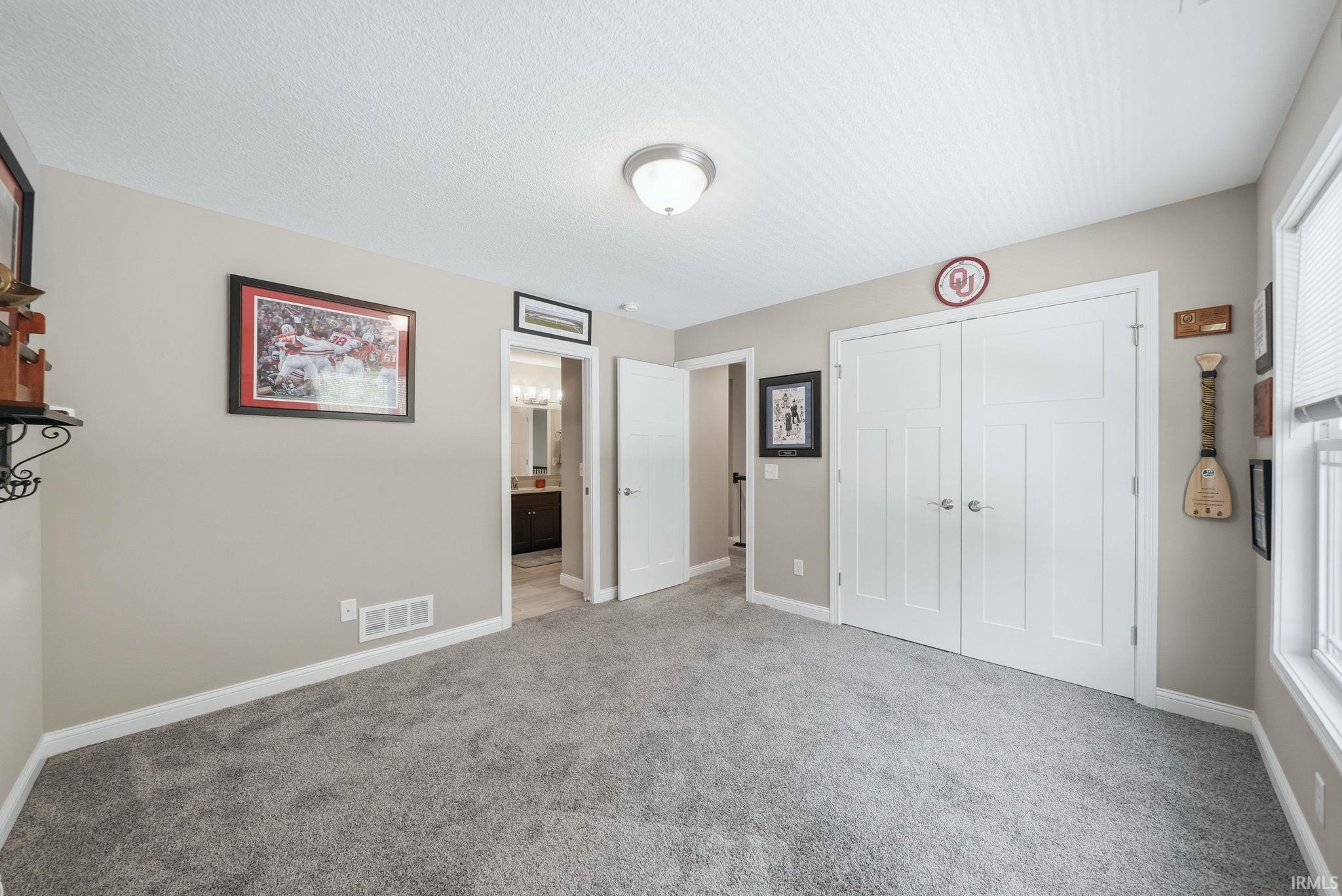 Spacious room featuring neutral carpeting, light-toned wall paint, and white trim