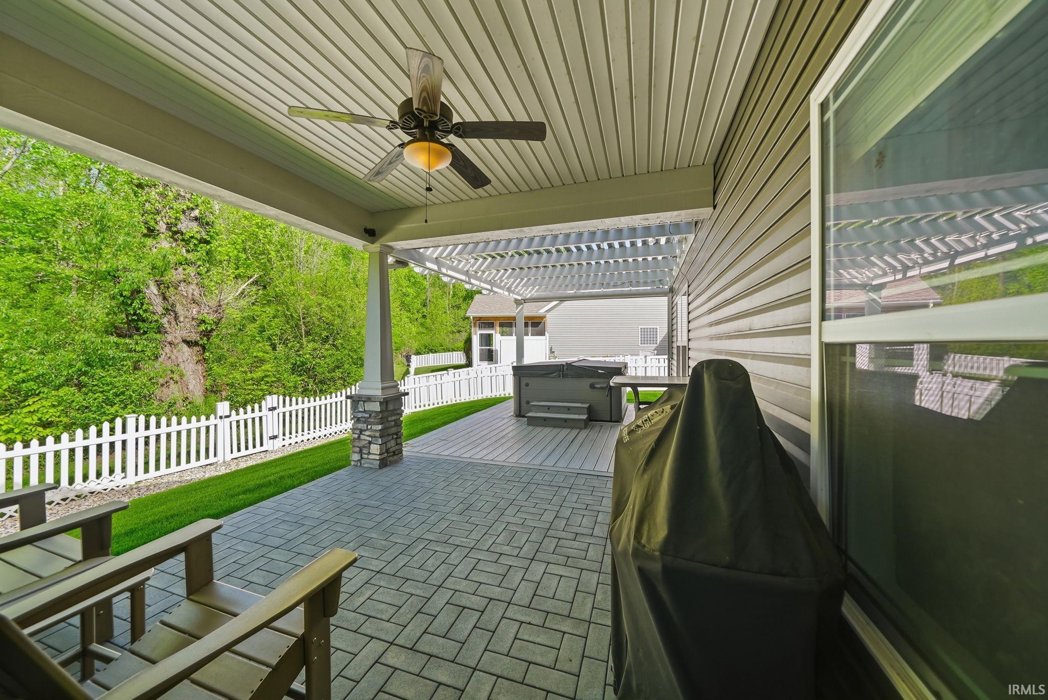 Covered patio featuring a ceiling fan, paver flooring, stone-clad pillar, and an attached pergola