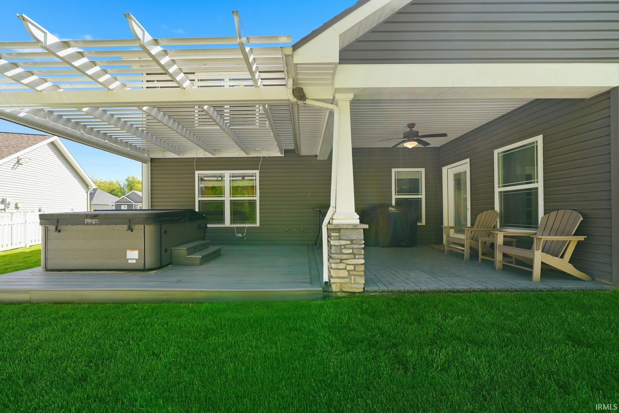 Expansive outdoor living area featuring a covered patio, louvered pergola, and a lush green lawn