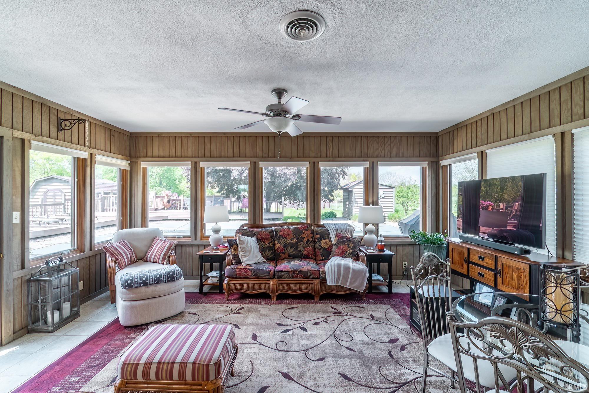 Sunroom featuring wood-paneled walls and a ceiling fan