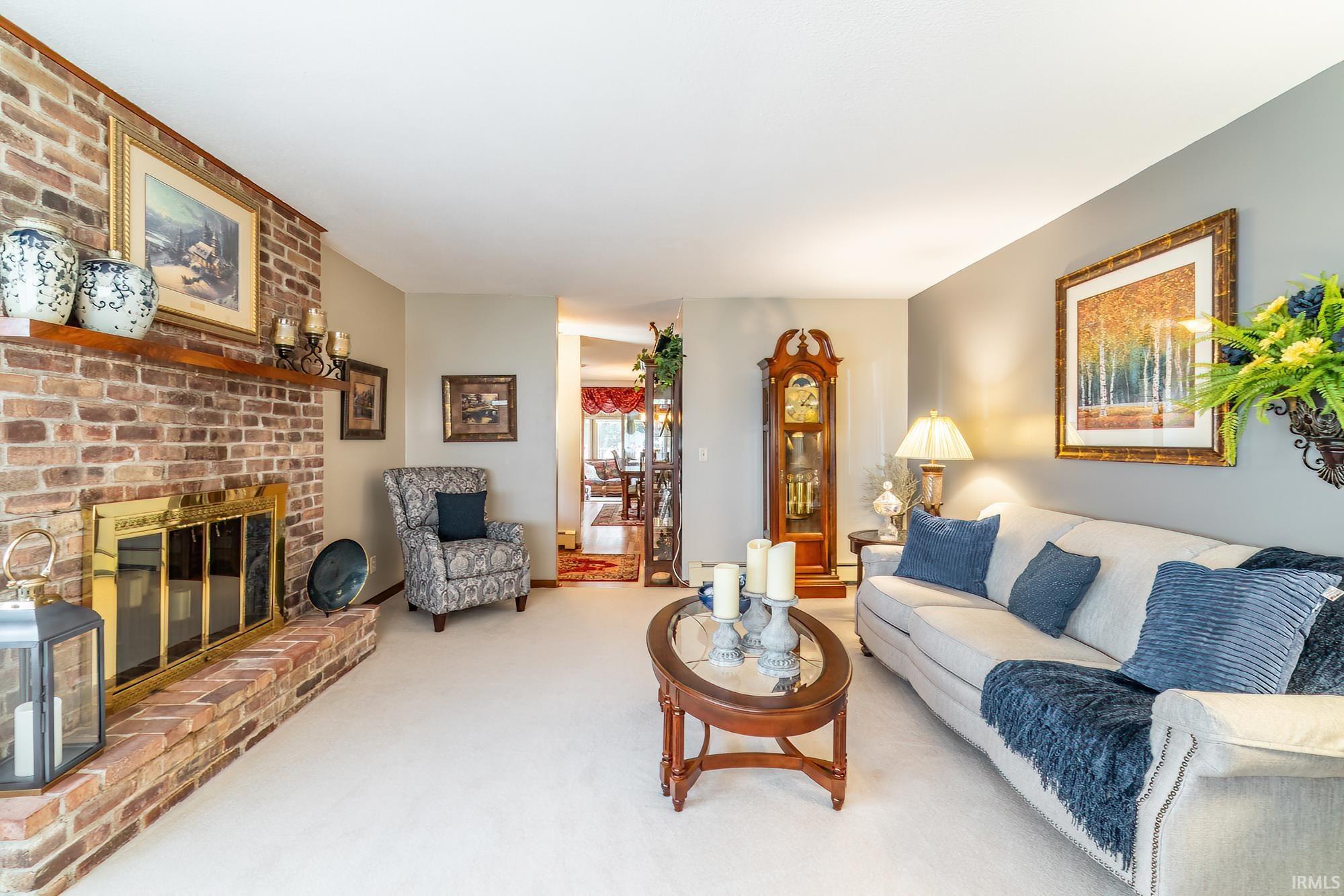 Living room featuring a prominent brick fireplace with a brass firebox and a wood mantel