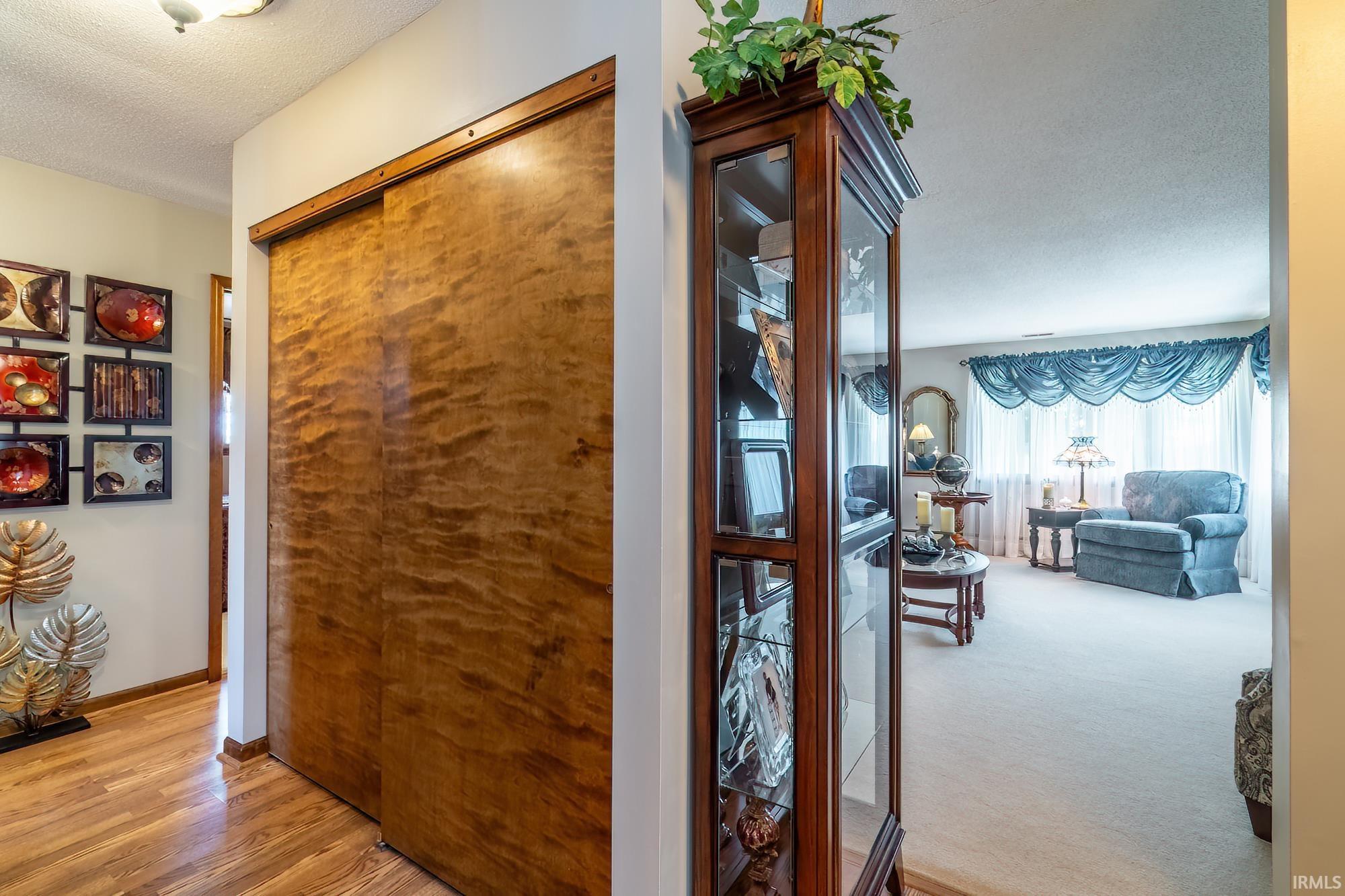 Hardwood flooring extending from the hallway, featuring a built-in display cabinet with glass doors