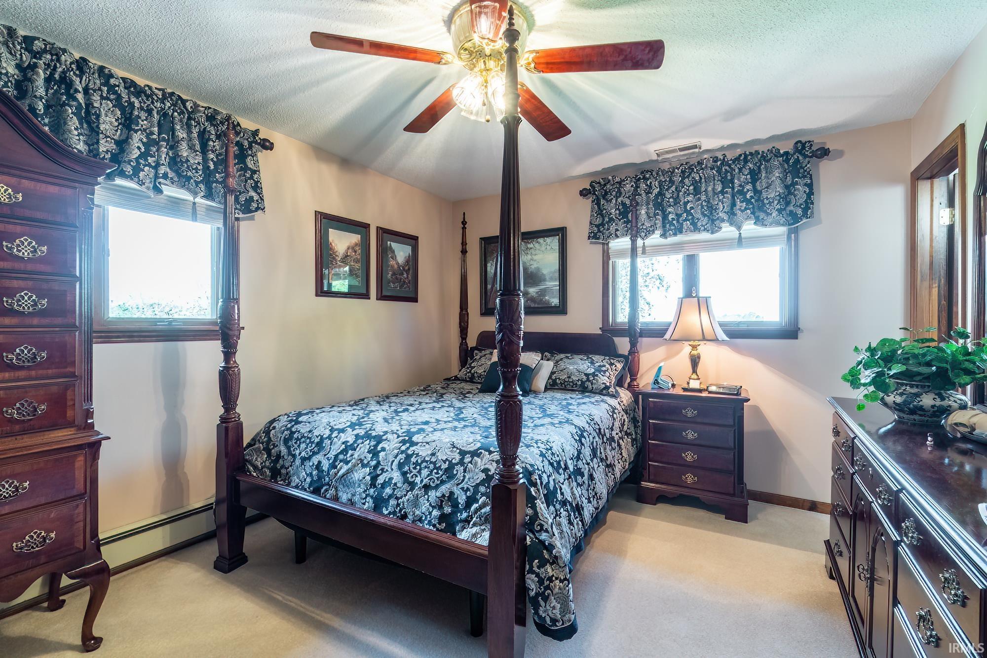 Carpeted interior space featuring a ceiling fan with integrated lighting, two windows with valances, and light-toned walls