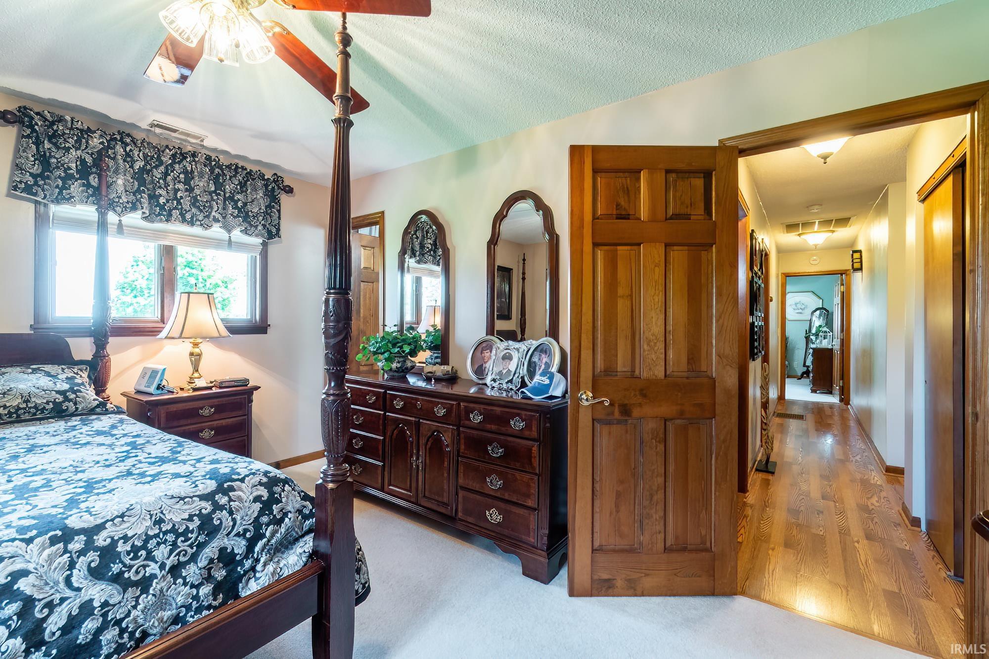 Bedroom featuring a window with natural light, a ceiling fan with light fixture, and plush carpeting