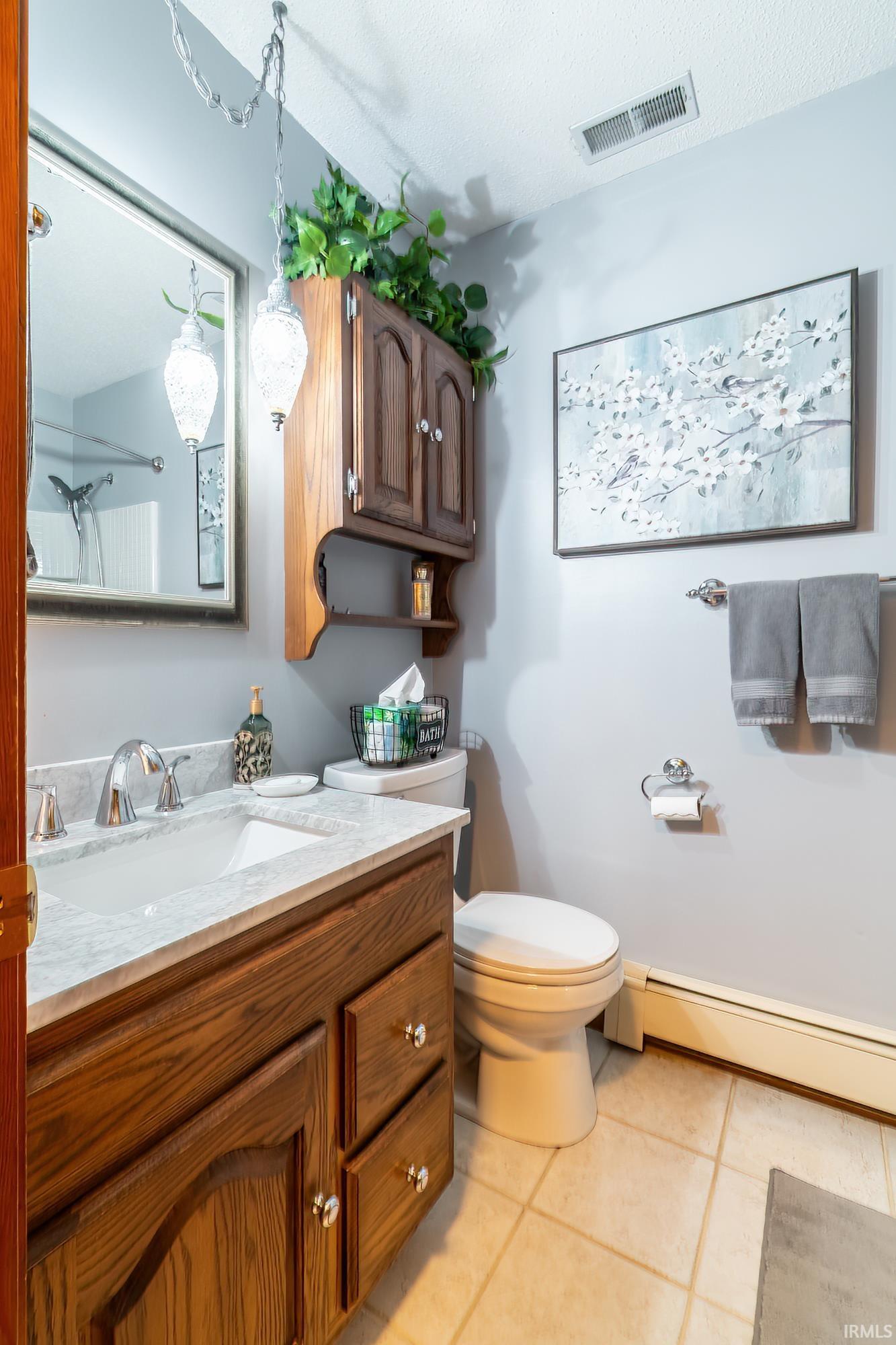 Bathroom featuring a wood-finish vanity with a light-toned countertop, a rectangular undermount sink, and polished chrome fixtures