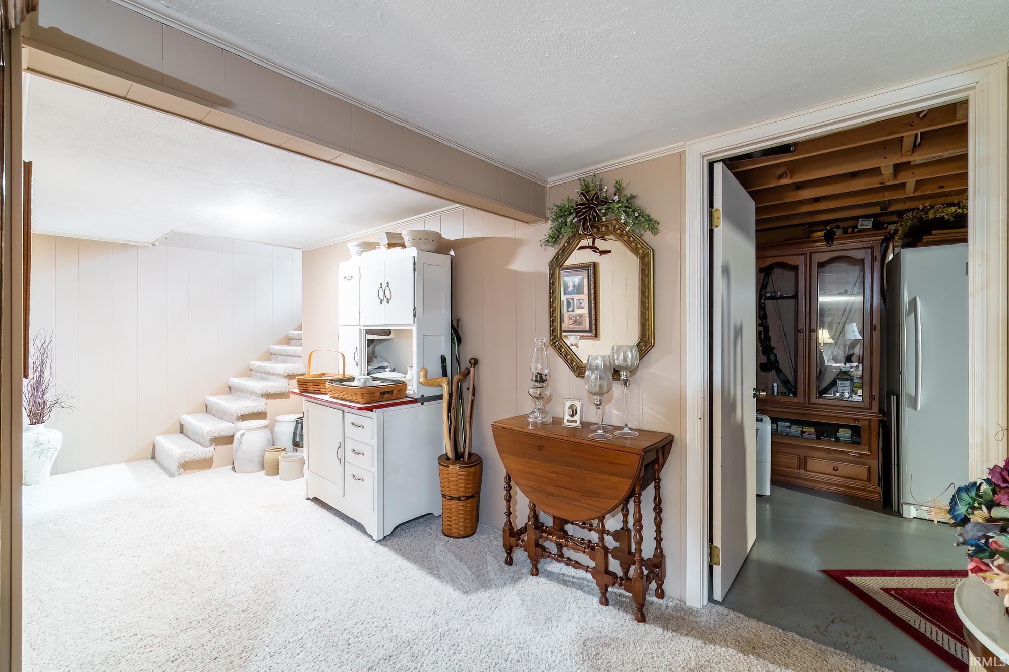 Carpeted lower level with a white paneled wall and a partial staircase