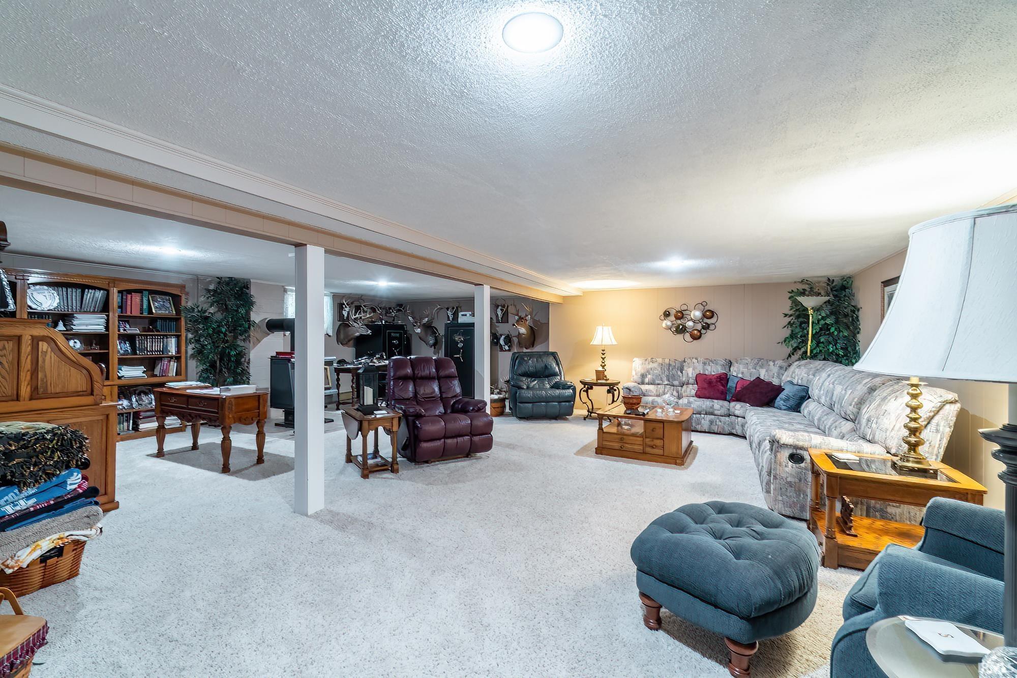 Spacious finished basement featuring recessed lighting, a neutral carpeted floor, and exposed support beams