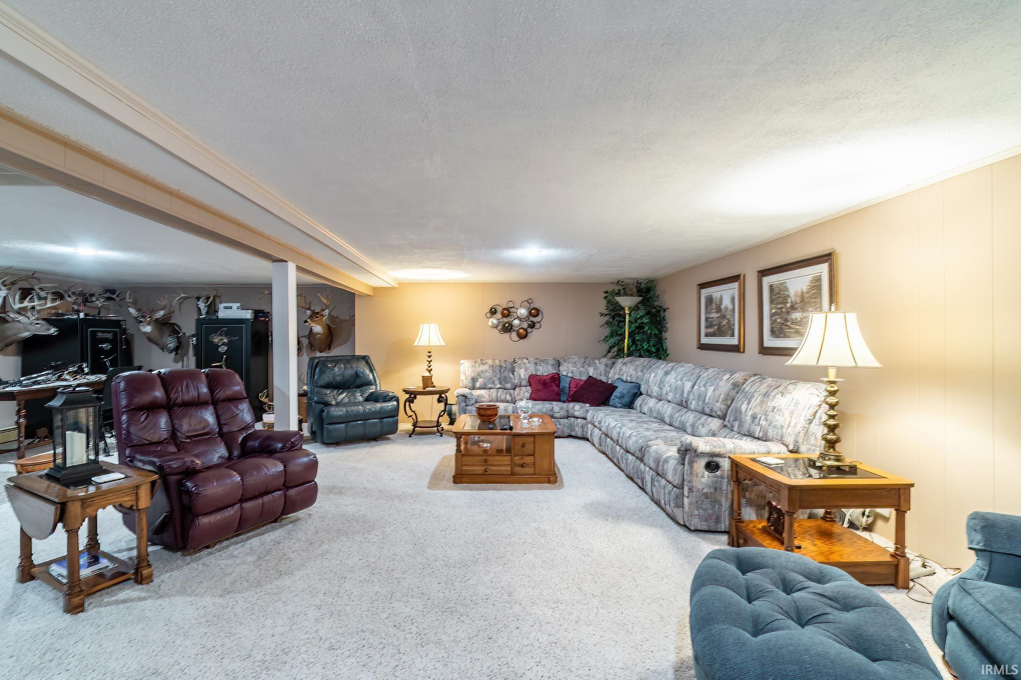 Spacious carpeted room featuring a large sectional sofa, recessed lighting, and a drop ceiling with decorative trim